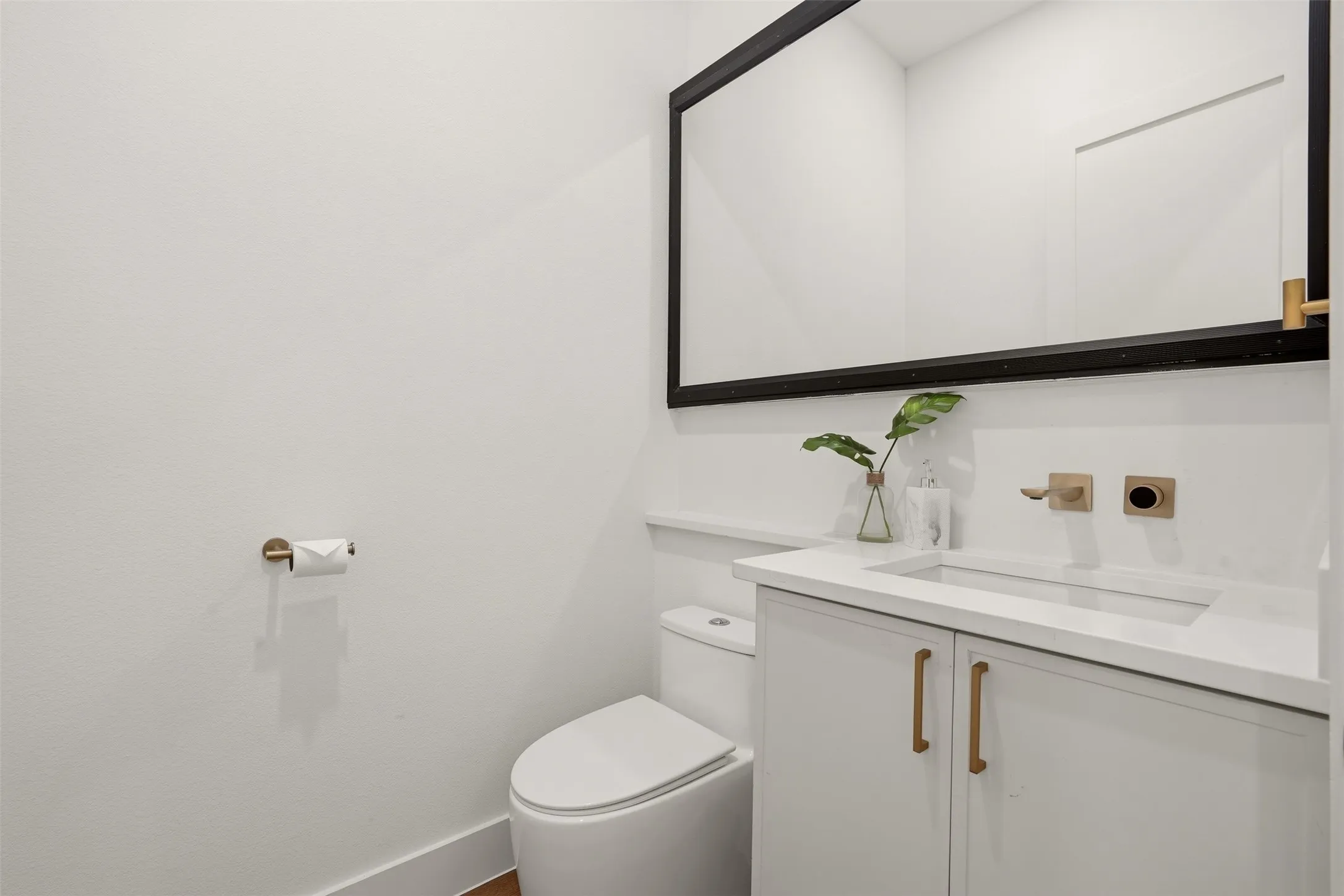 White vanity with integrated sink, gold-tone hardware, and a wall-mounted faucet