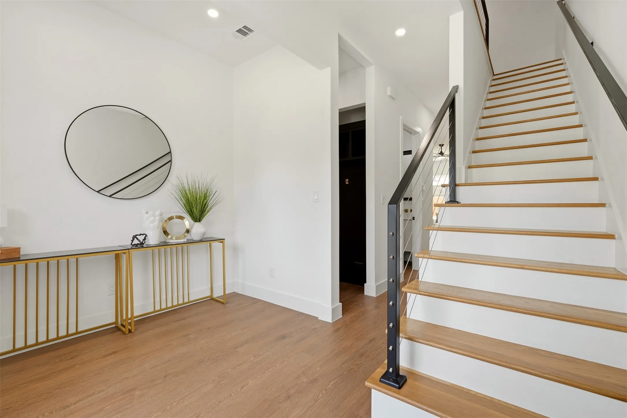 Wood-finish flooring, recessed lighting, white walls, and a staircase with wood treads and a cable railing system