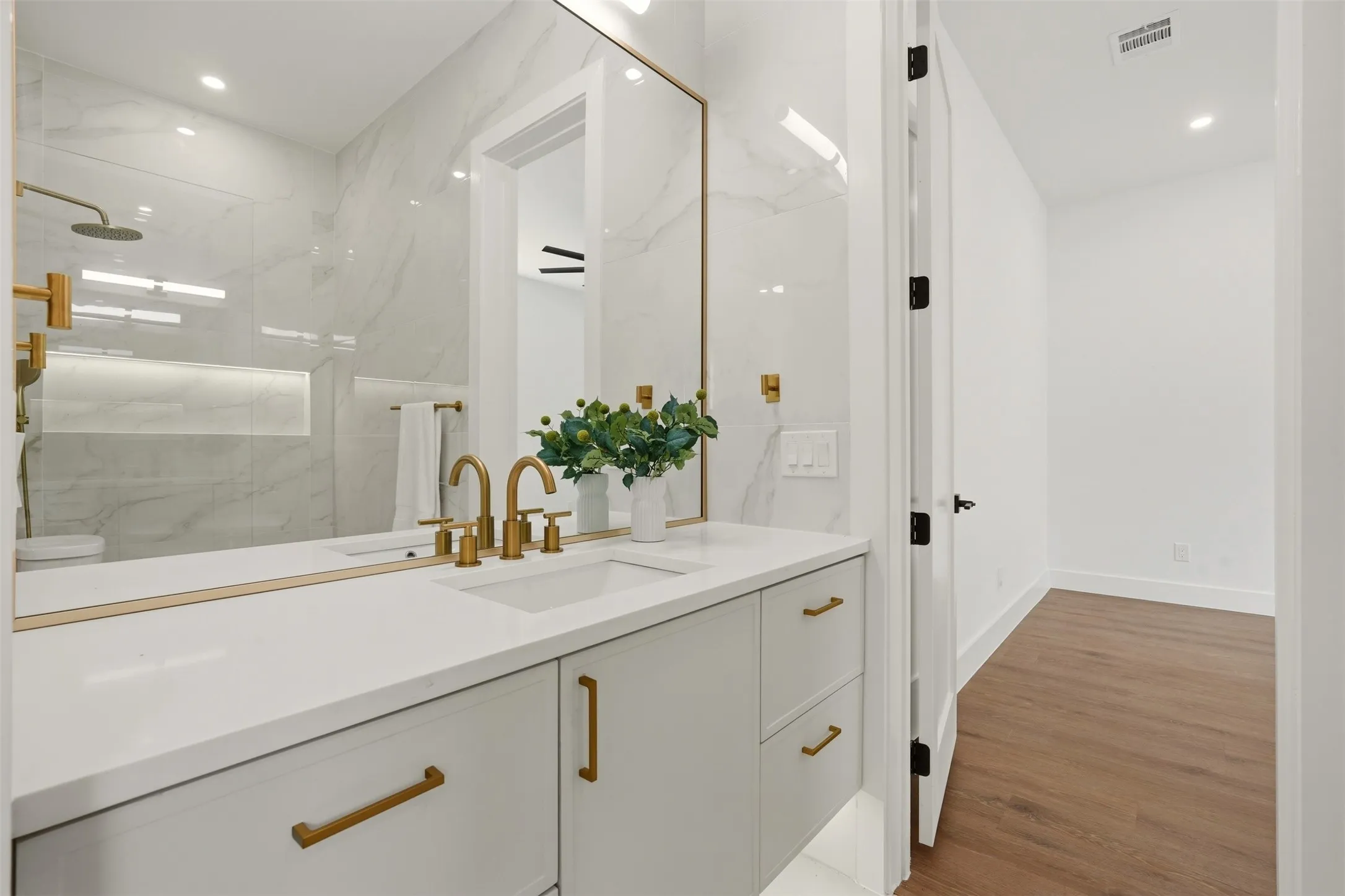 Double vanity with integrated sinks, gold-finish fixtures, and a large framed mirror