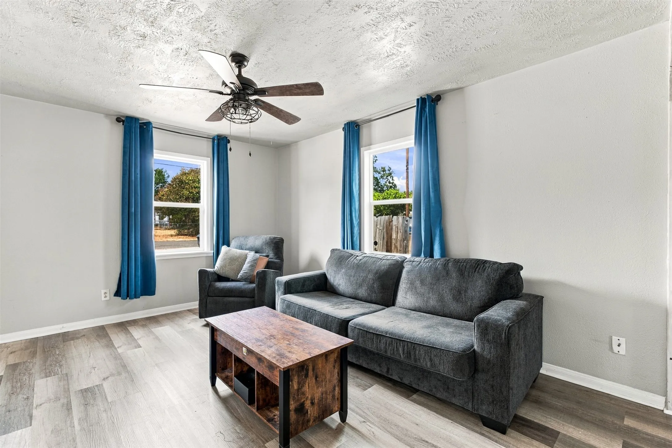 Wood-finish flooring, light gray walls, and a ceiling fan with integrated lighting