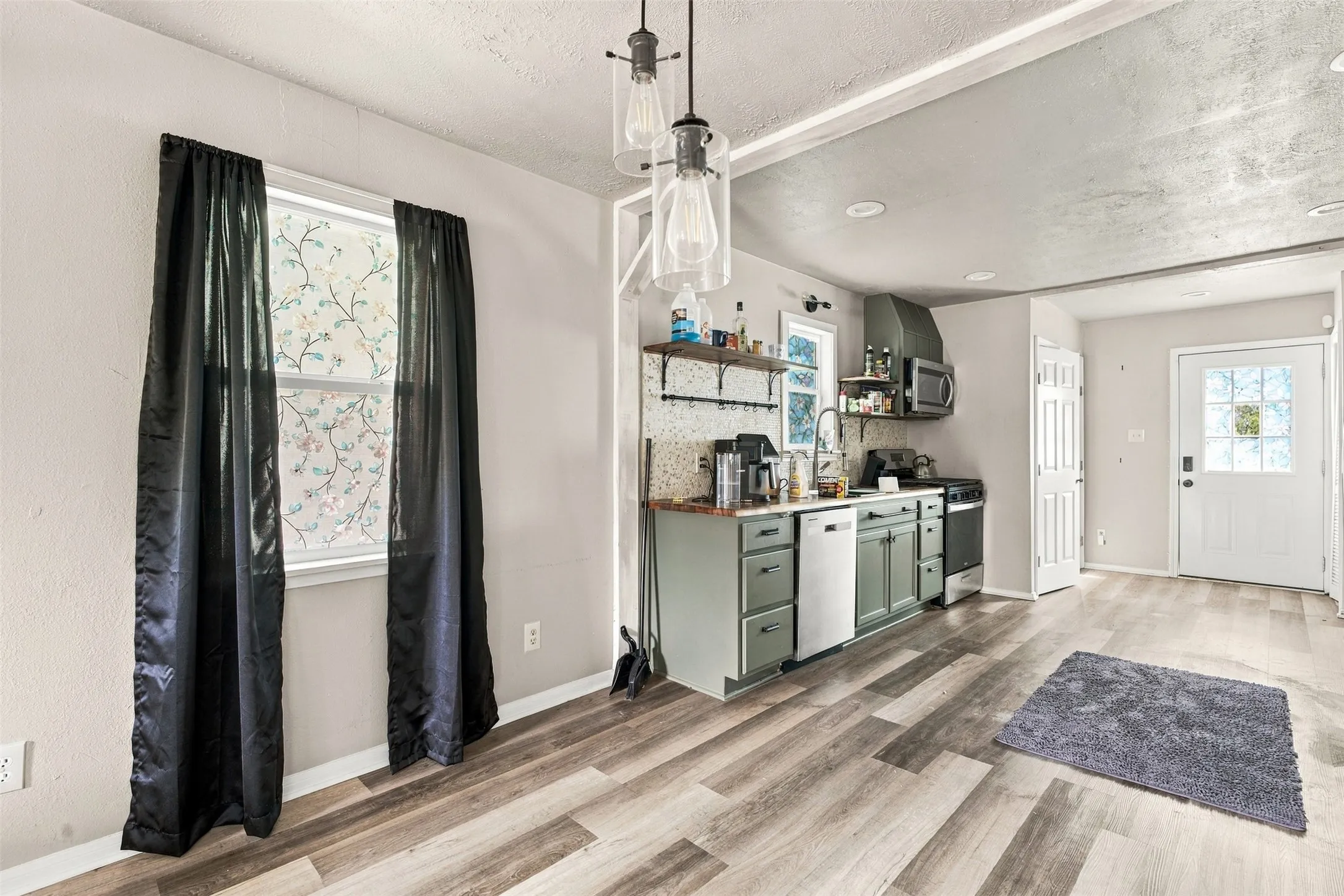 Contemporary kitchen with open shelving, wood-finish flooring, a white paneled door, and pendant lighting