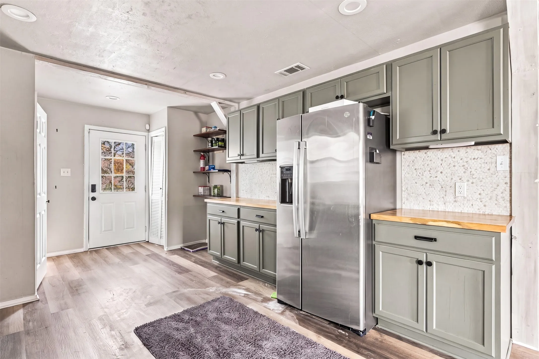 Kitchen featuring gray cabinetry, wood-finish countertops, and a speckled backsplash