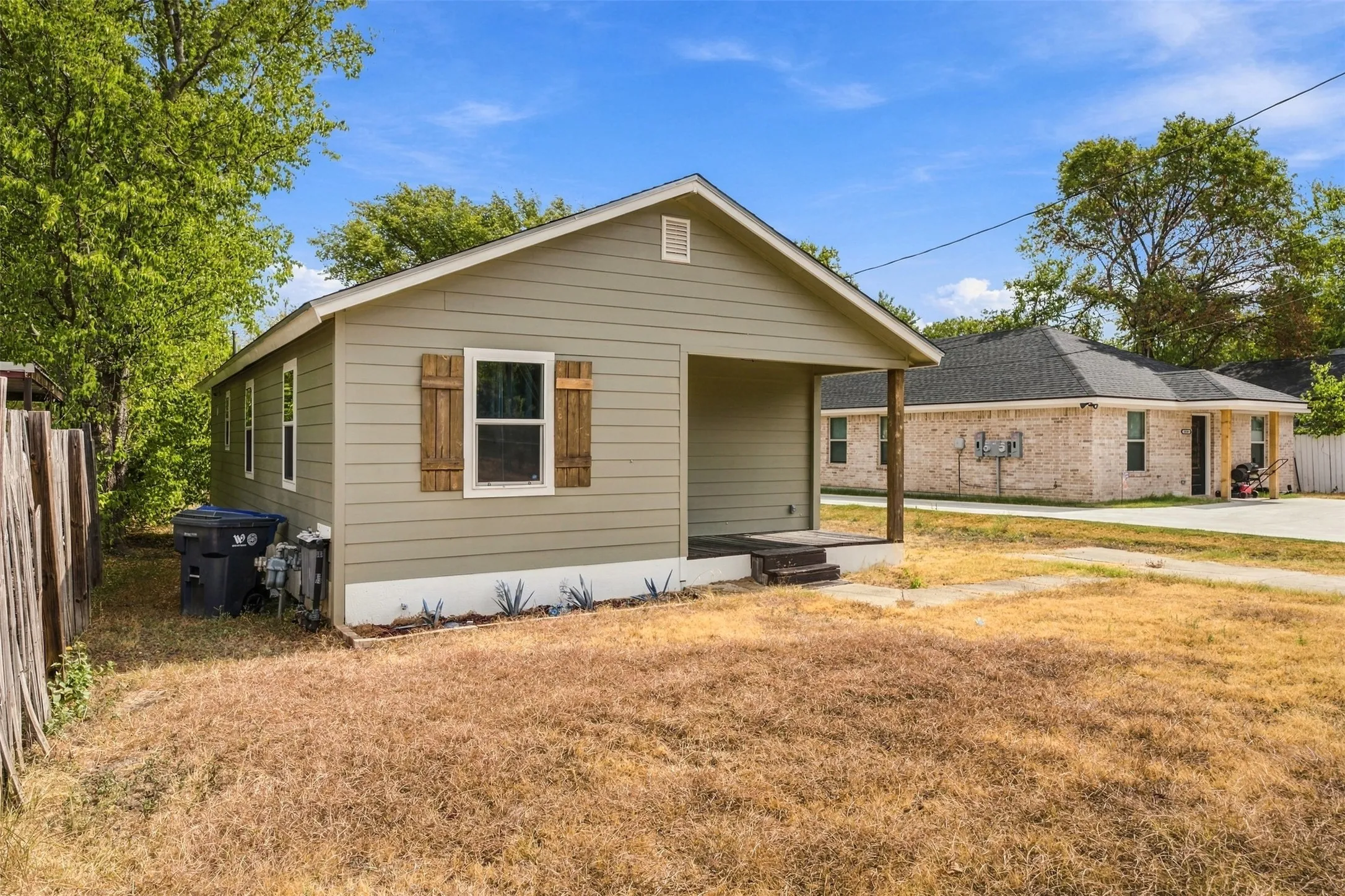 Siding exterior with wood shutters, covered front entry, and a pitched roof