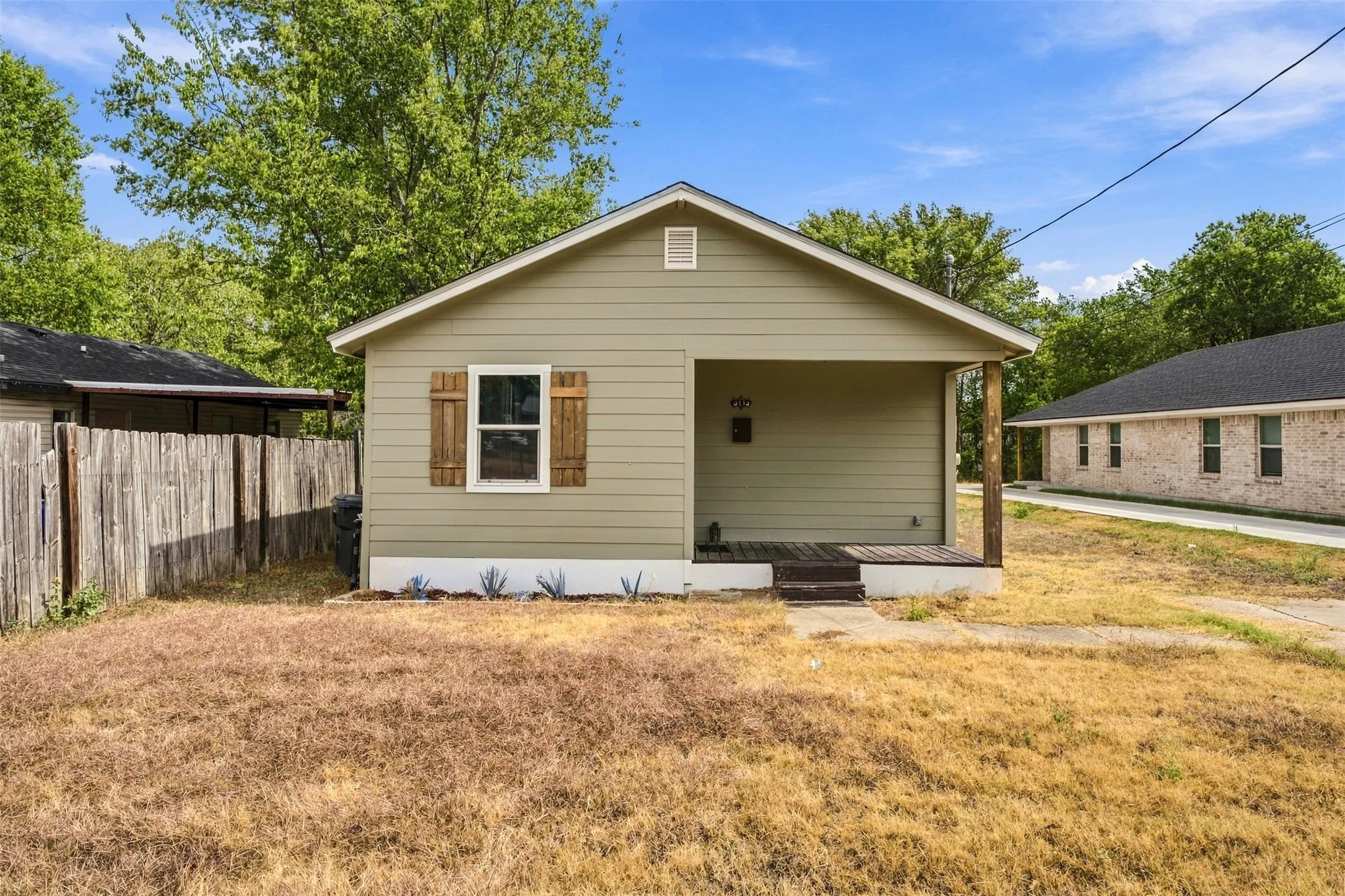 Front exterior with horizontal siding, a covered porch, and decorative wood window shutters