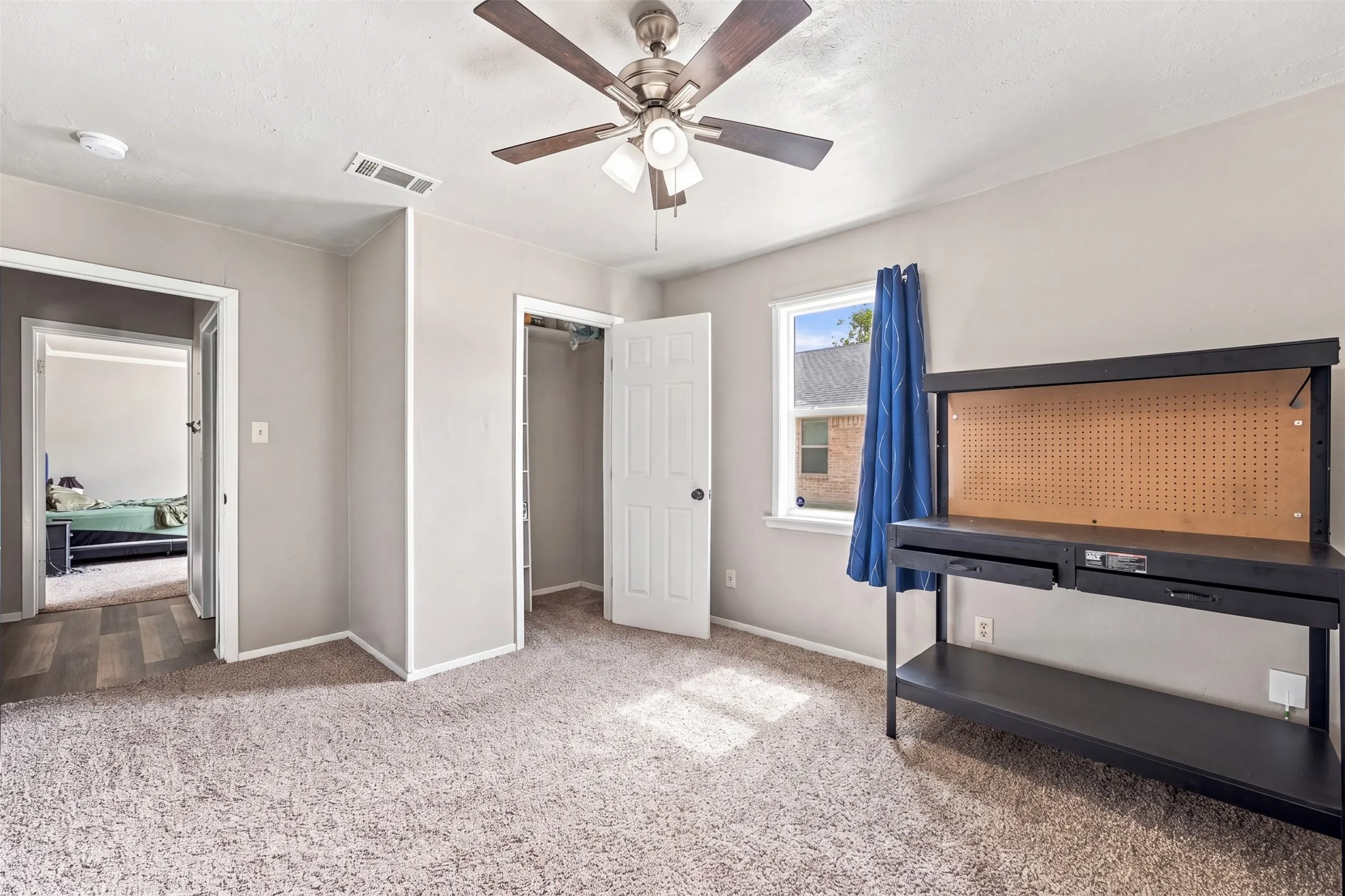 Carpeted flooring, ceiling fan with integrated lighting, window with trim, white interior doors