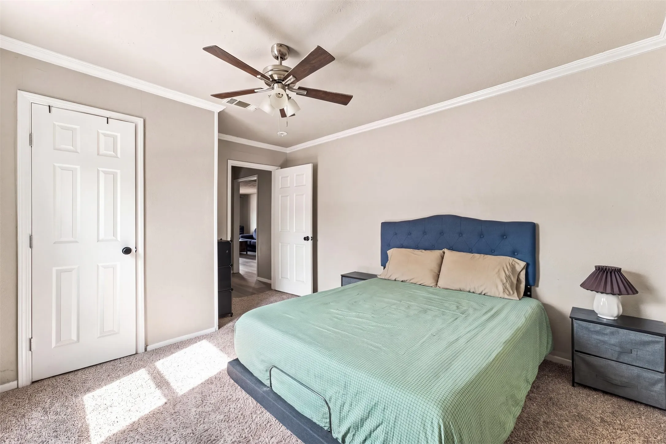 Ceiling fan with wood-finish blades, crown molding, and textured carpeting
