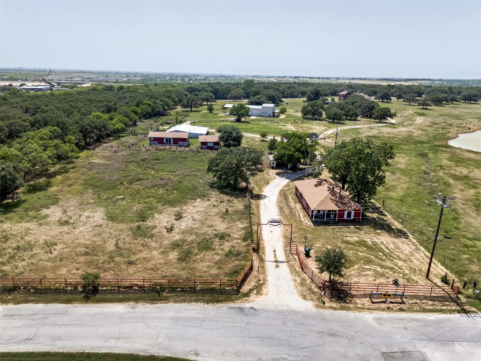 Expansive property featuring multiple structures, mature trees, a private drive, and a pond