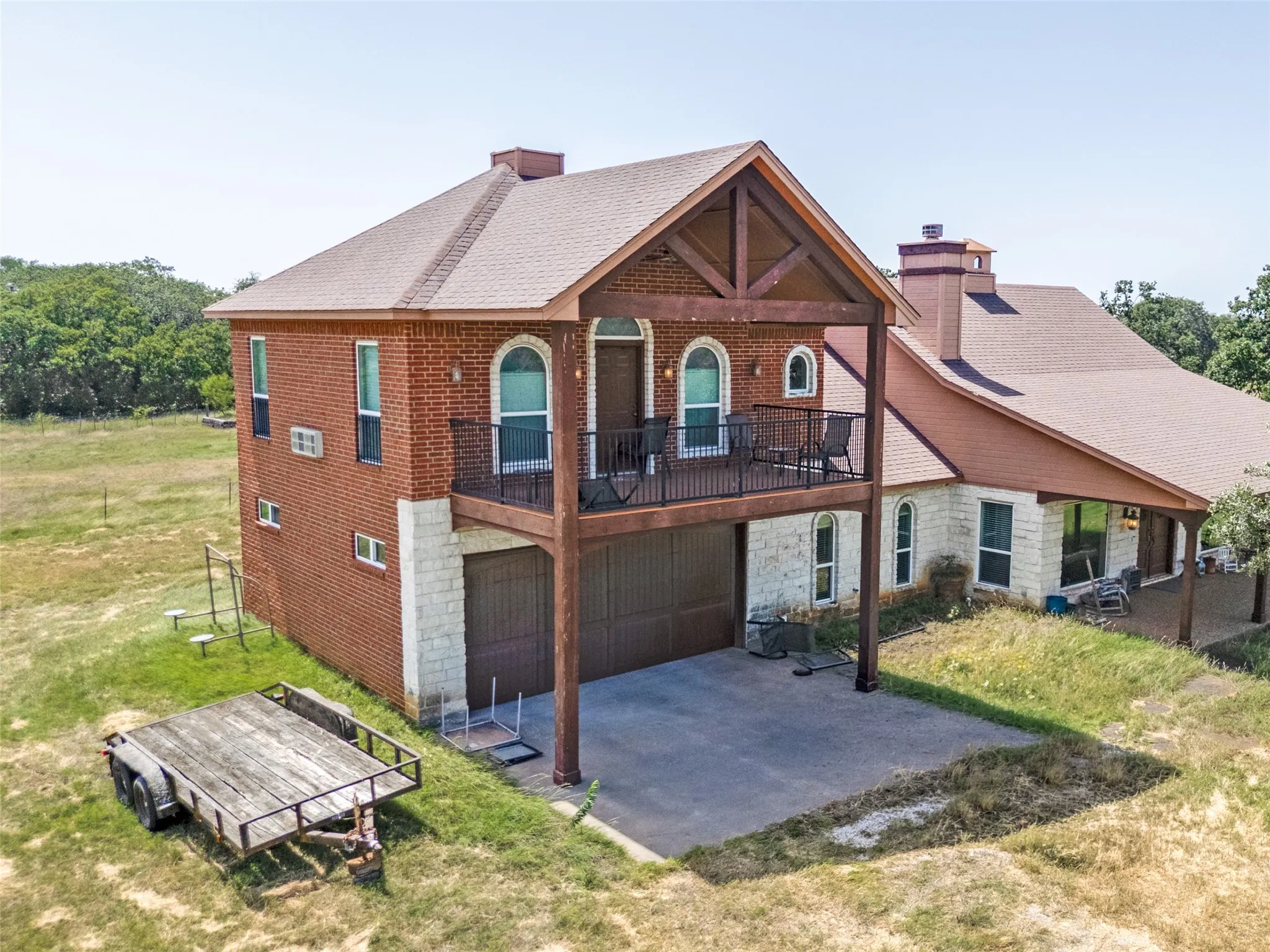 Brick and stone exterior with arched windows, covered balcony featuring a wrought iron railing, and a two-car garage