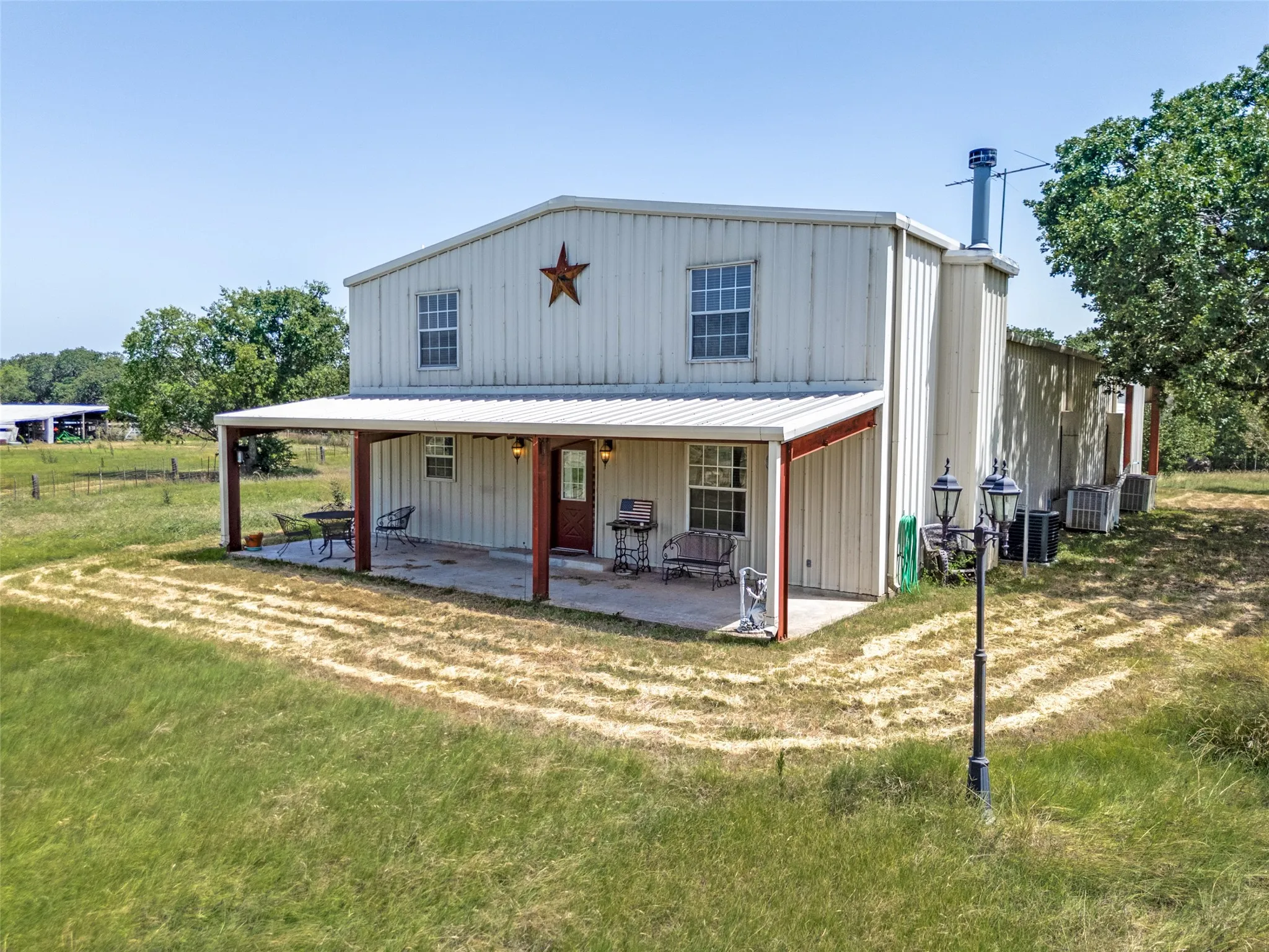 Metal-sided structure featuring a covered front porch, an overhead metal roof, and multiple exterior windows