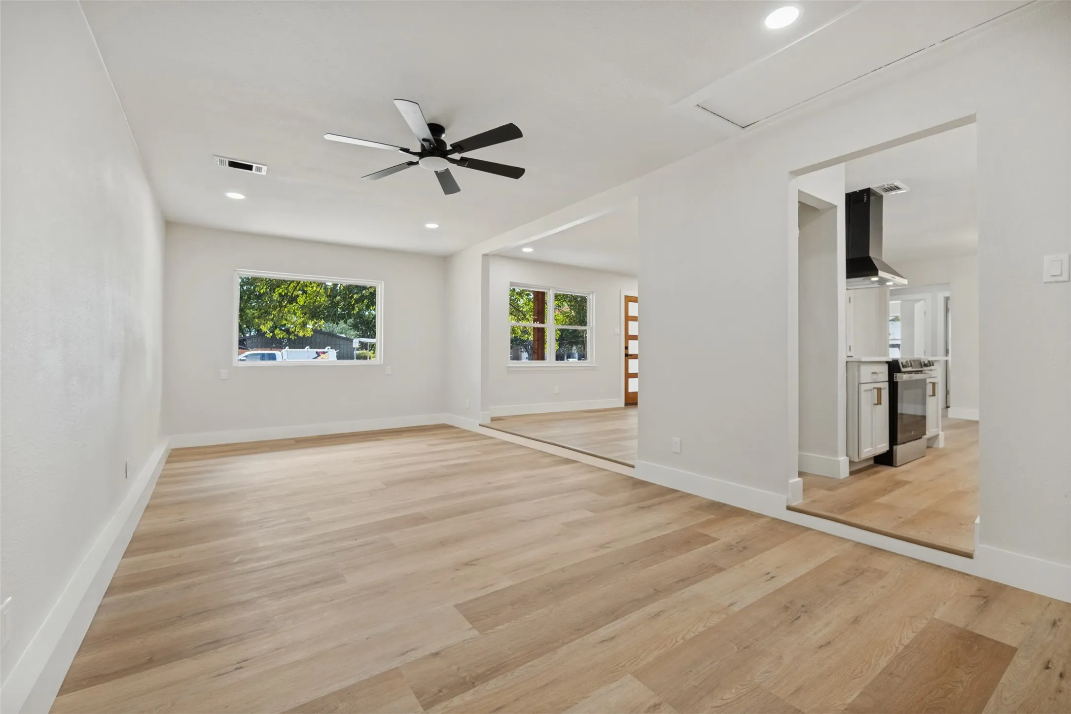 Recessed lighting, wood-finish flooring, and a modern ceiling fan in a brightly lit interior space