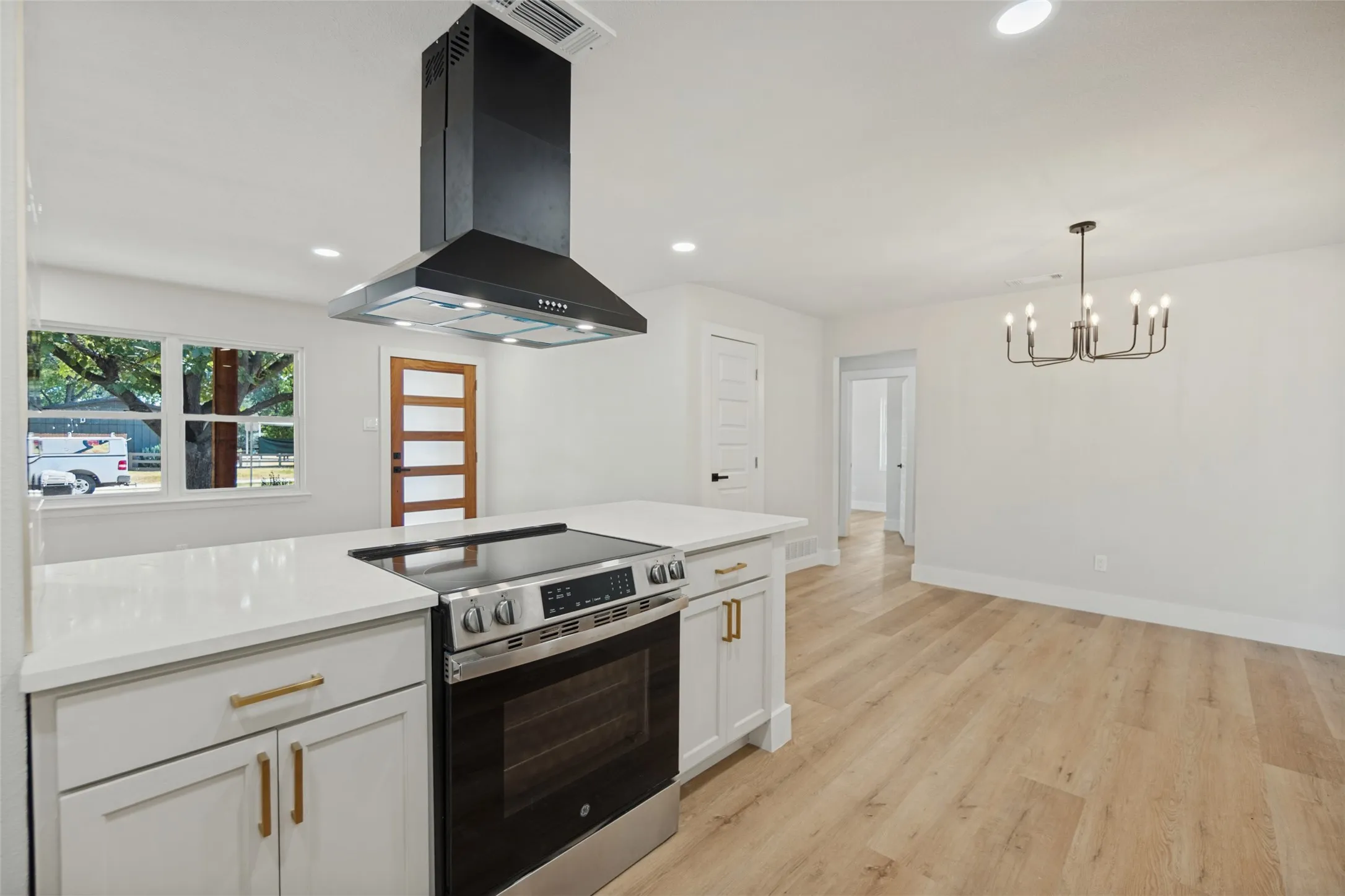 Kitchen island with a built-in electric range, stainless steel oven, and a black range hood