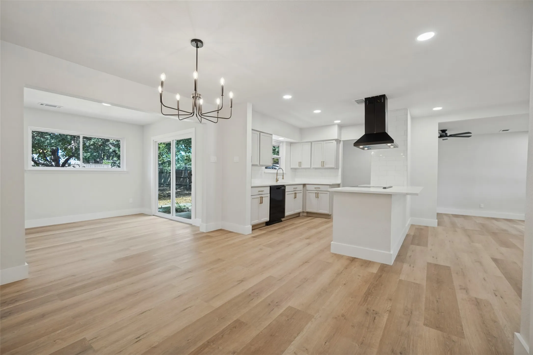 Open-concept living space featuring wood-finish flooring, a modern chandelier, and sliding glass doors to the exterior