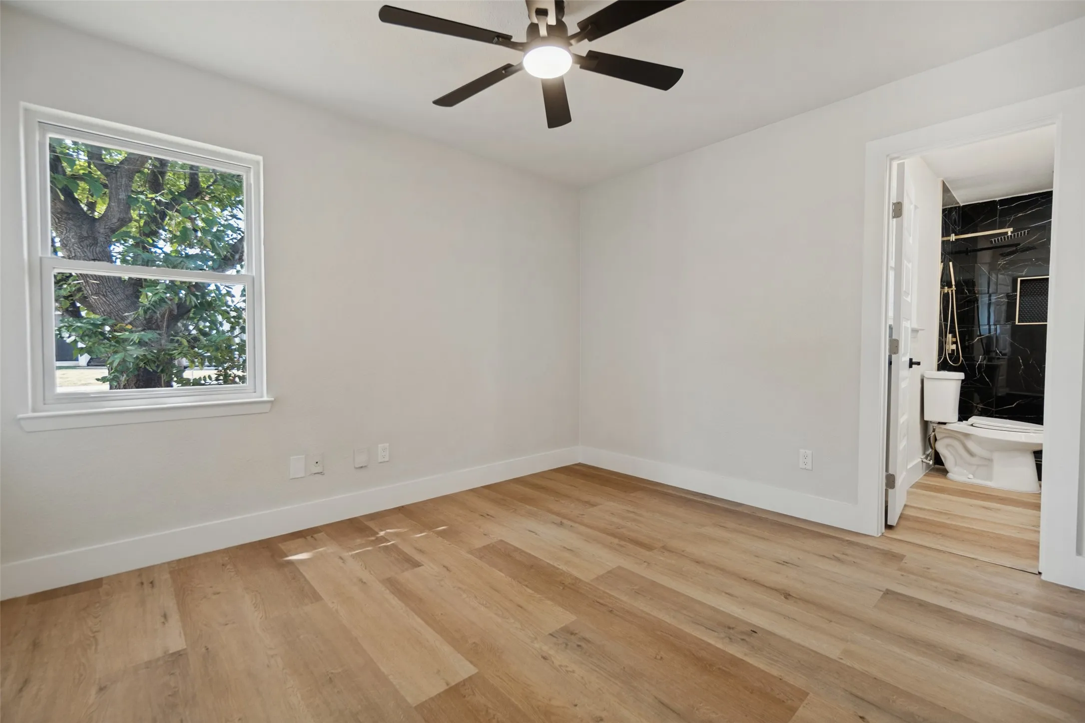 Wood-finish flooring, white walls, and a ceiling fan with integrated lighting
