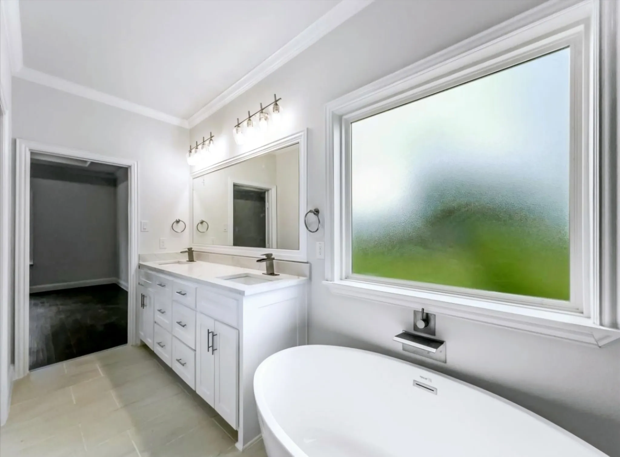 Full bathroom featuring double vanity, a freestanding tub, ornamental molding, and light tile patterned floors