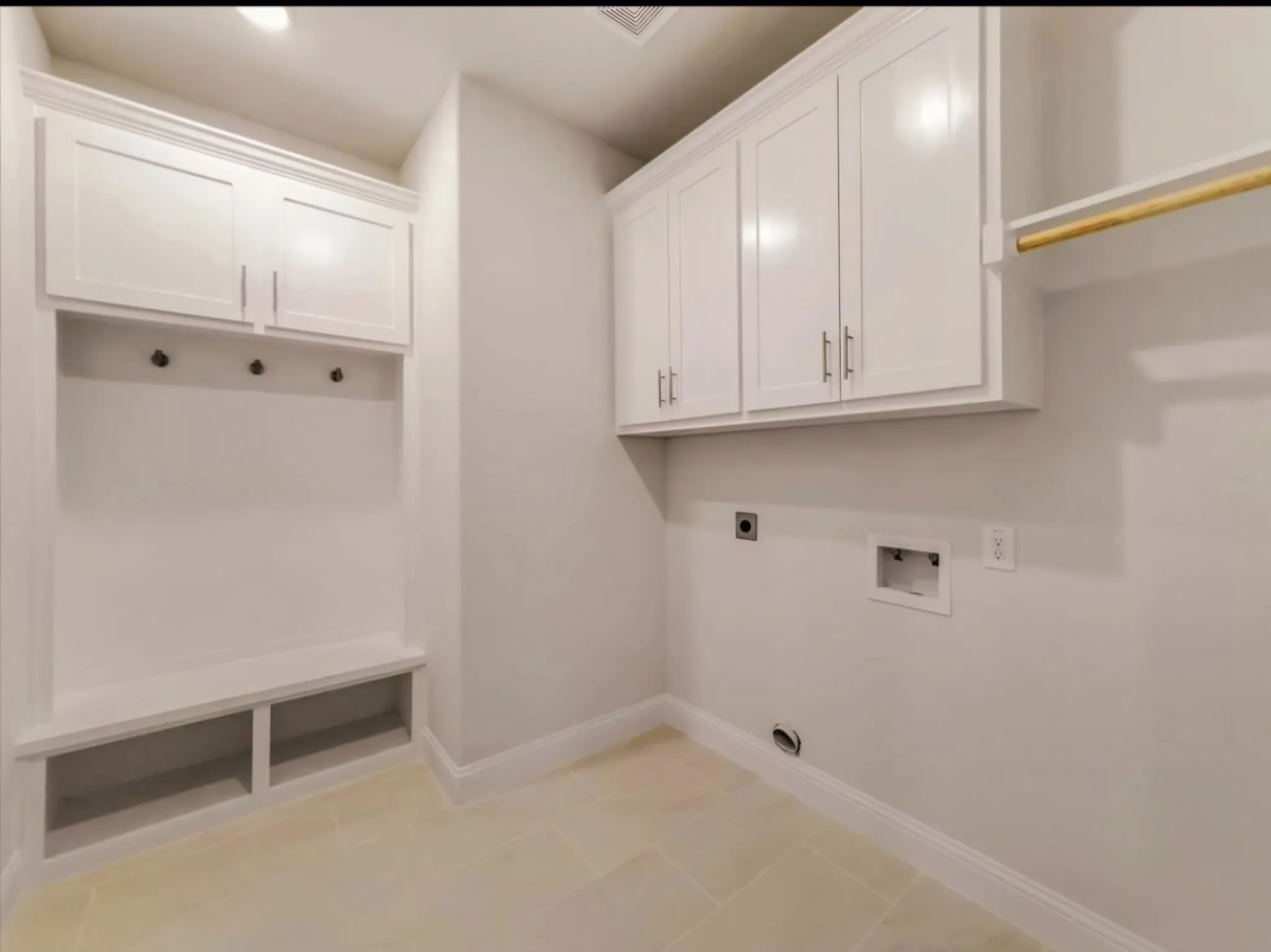 Laundry area with electric dryer hookup, hookup for a washing machine, light tile patterned floors, and cabinet space