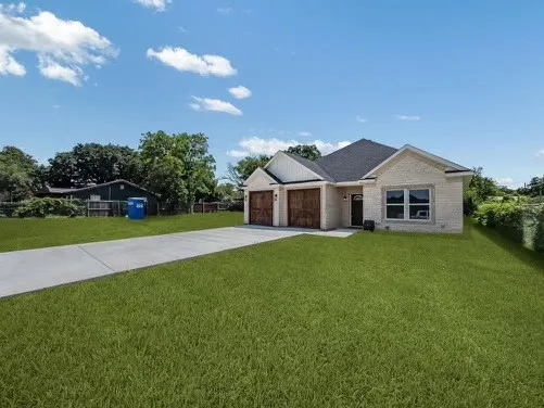 View of front of property featuring a front lawn, driveway, an attached garage, and brick siding
