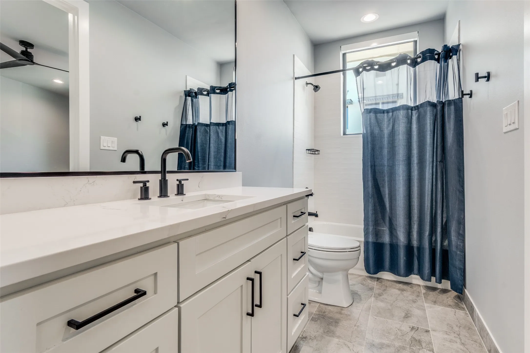 White vanity with shaker-style cabinetry, matte black hardware, and a white countertop