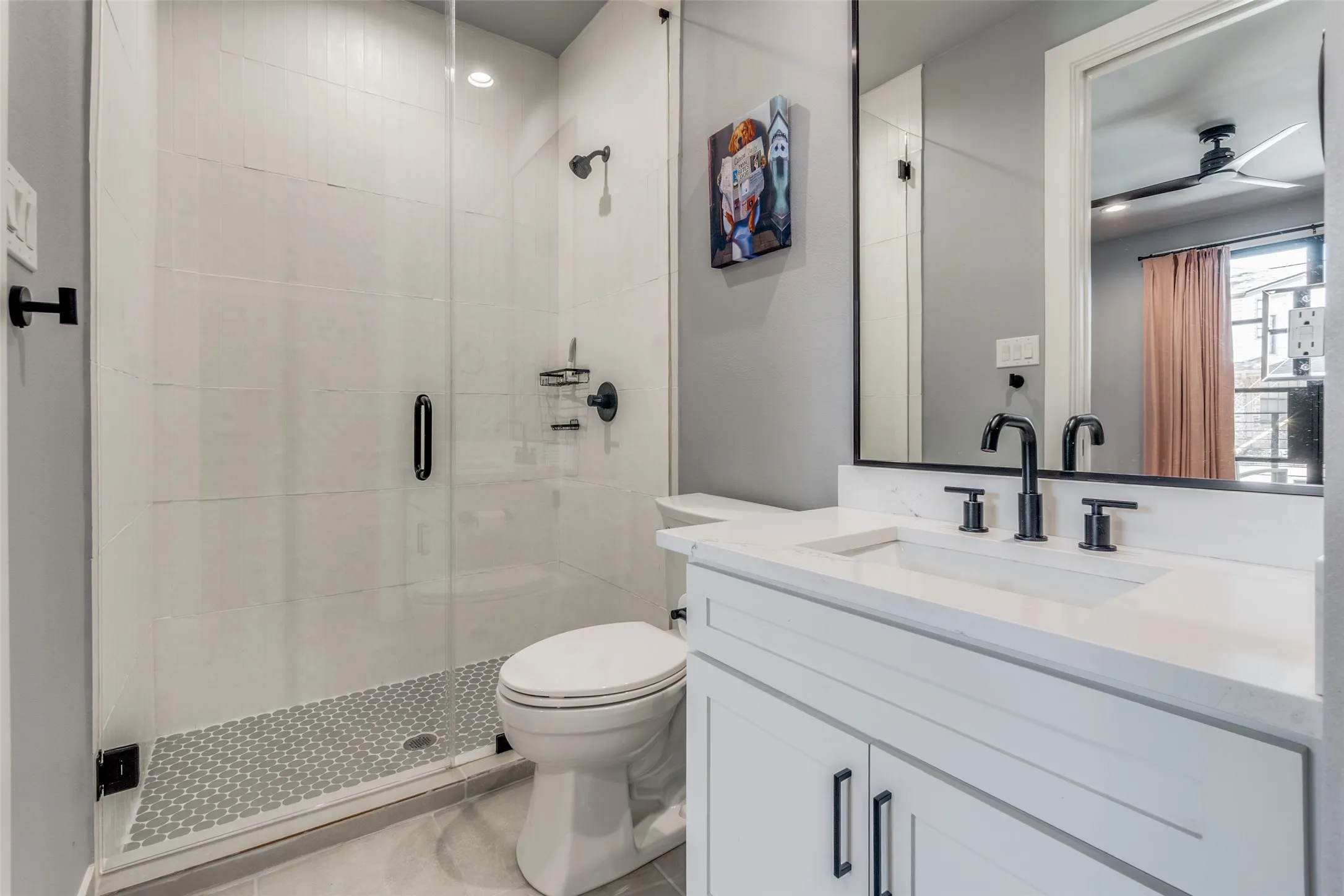 Walk-in shower with clear glass enclosure and mosaic tile floor