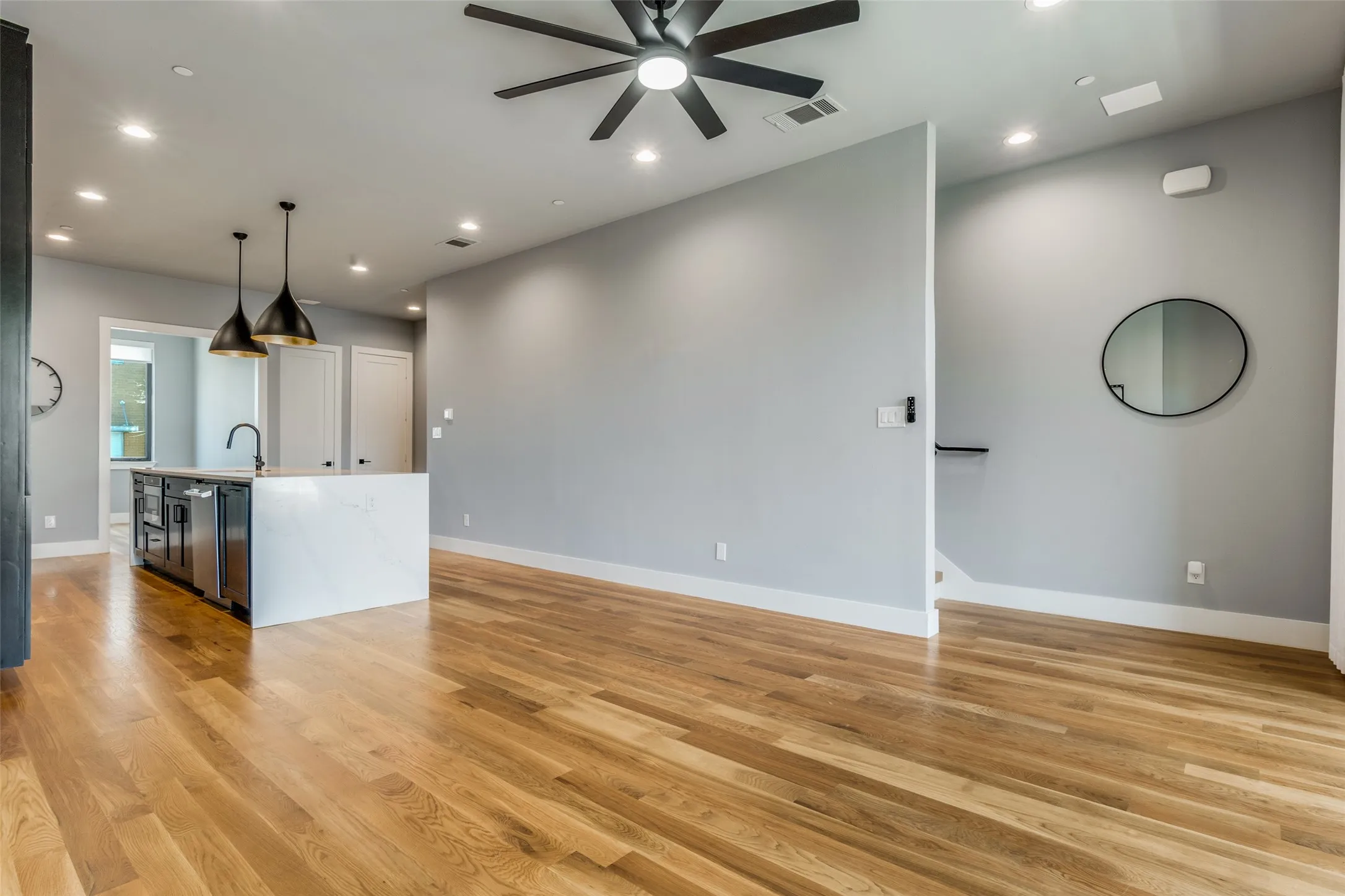 Hardwood flooring, recessed lighting, ceiling fan, kitchen island with quartz countertop, and pendant lighting
