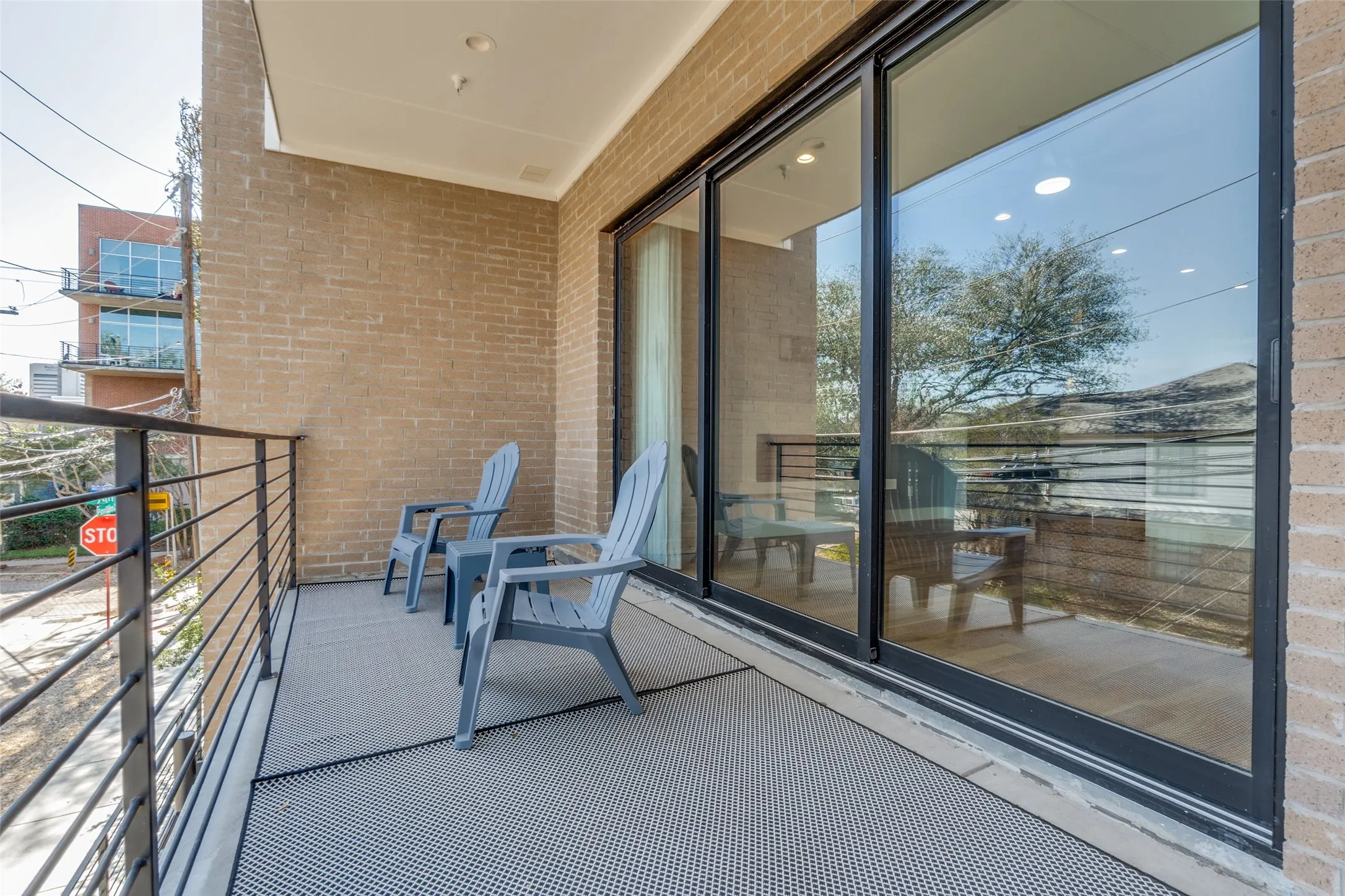 Balcony featuring brick exterior, black metal railing, and large sliding glass doors