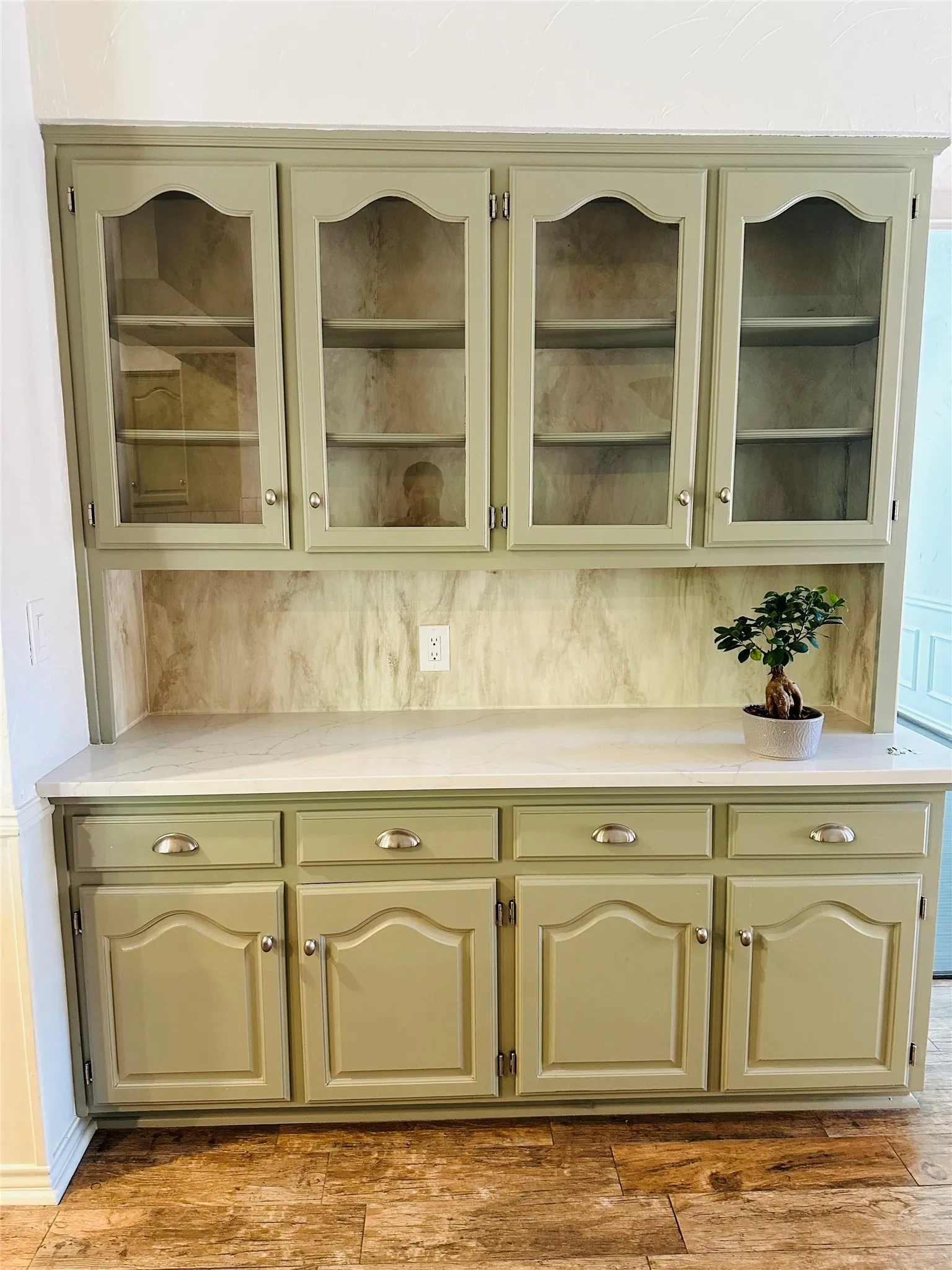 Built-in cabinetry with glass-front upper doors, lower storage cabinets, and a solid surface countertop