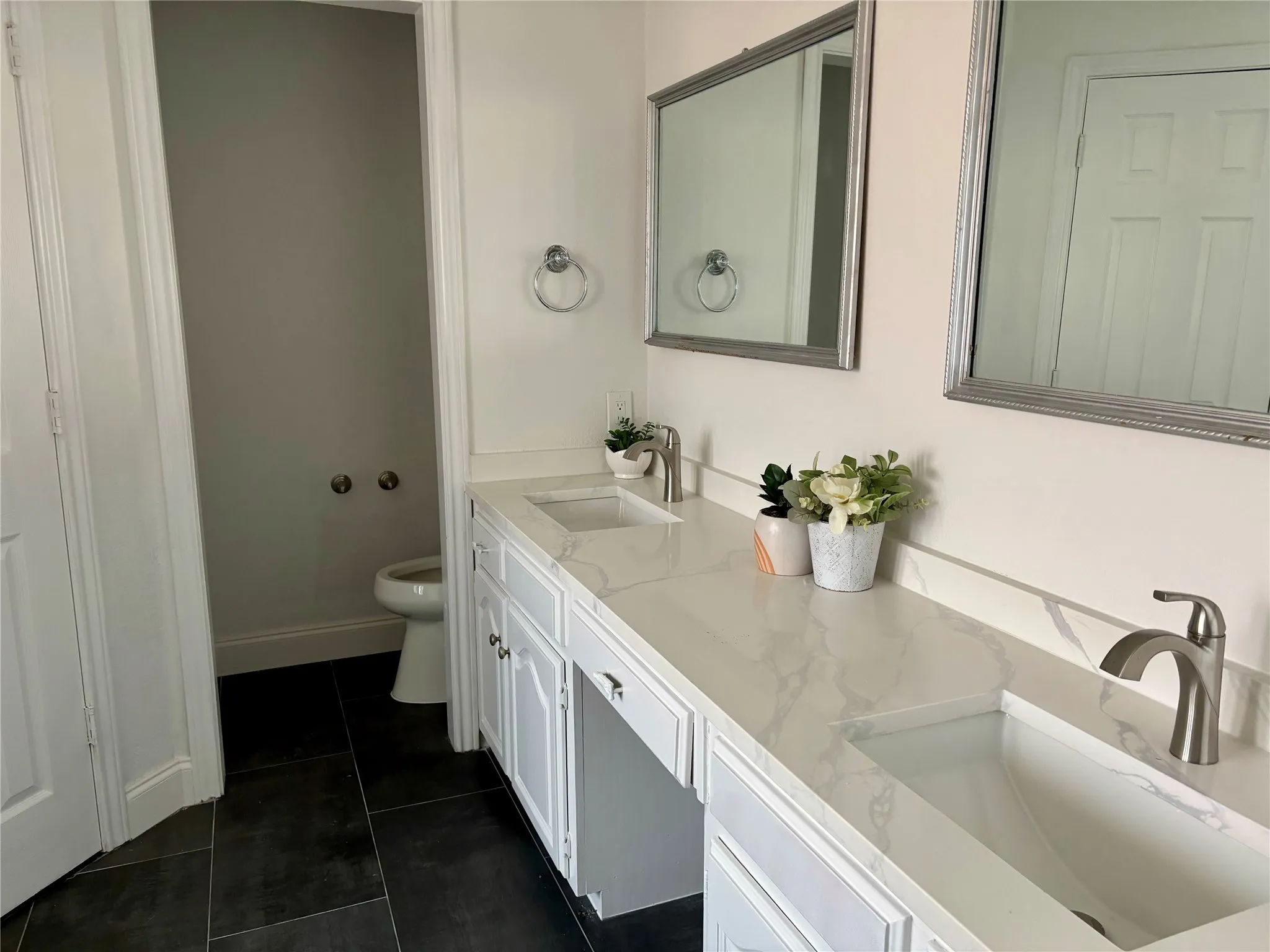 Dual vanity with integrated sinks, white cabinetry, and quartz countertops, complemented by contemporary brushed nickel faucets and framed mirrors