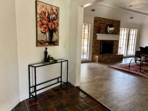 Brick fireplace with a white mantel, arched doorways, and tile flooring