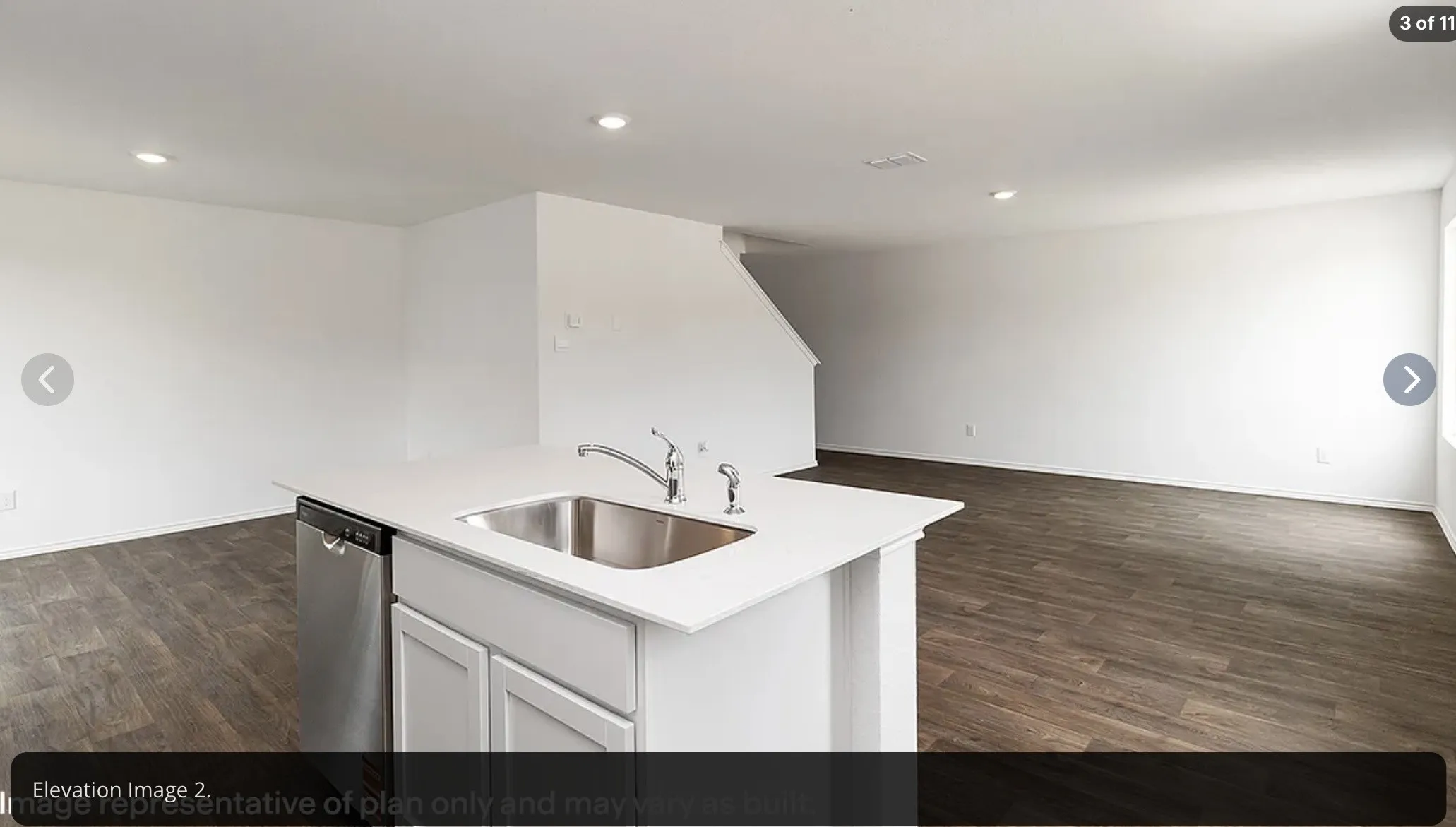 Kitchen island with a stainless steel sink, chrome faucet, white cabinetry, and white countertops