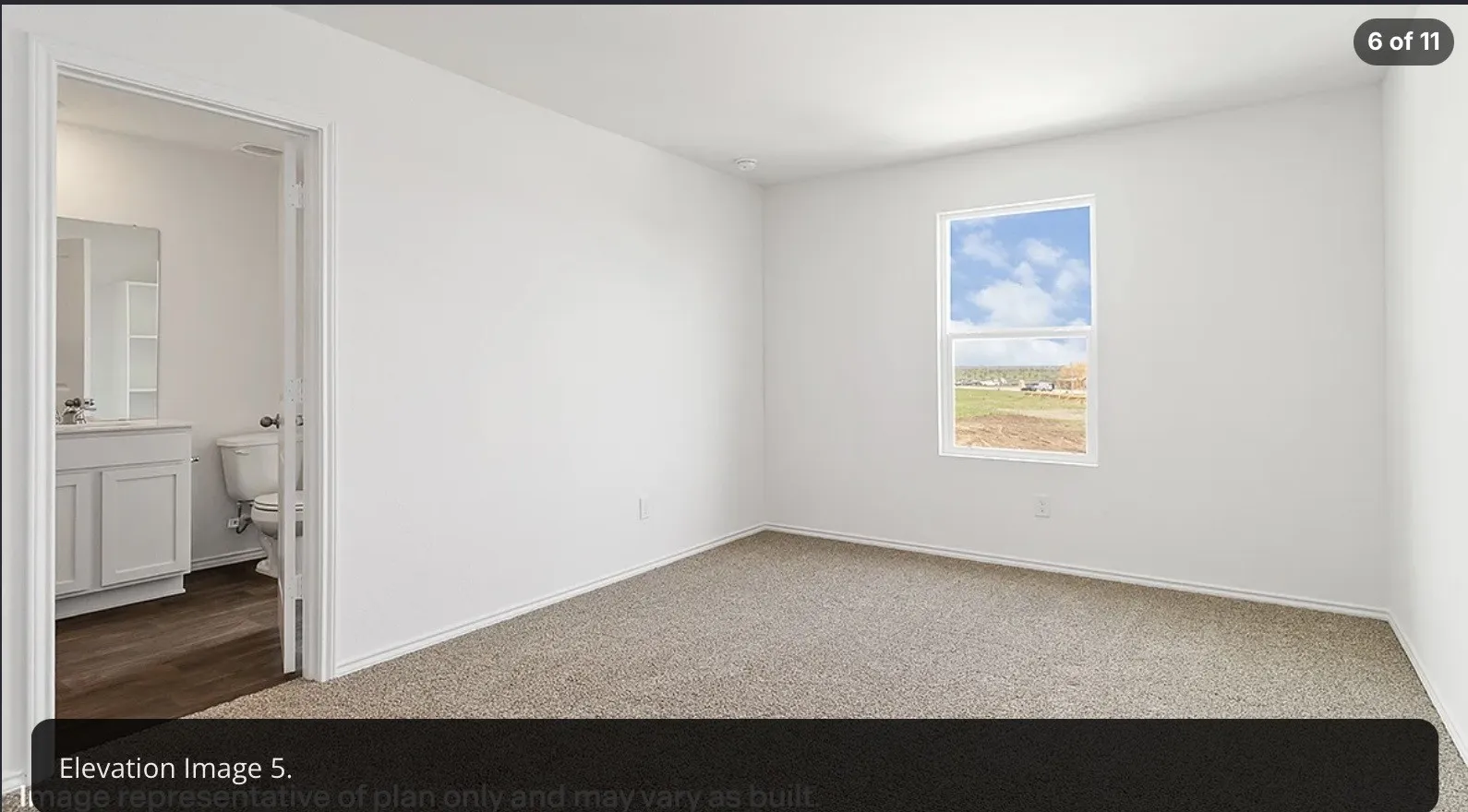 Carpeted flooring, single window, white wall finishes, and an entryway to a bathroom featuring a vanity with a mirror and toilet