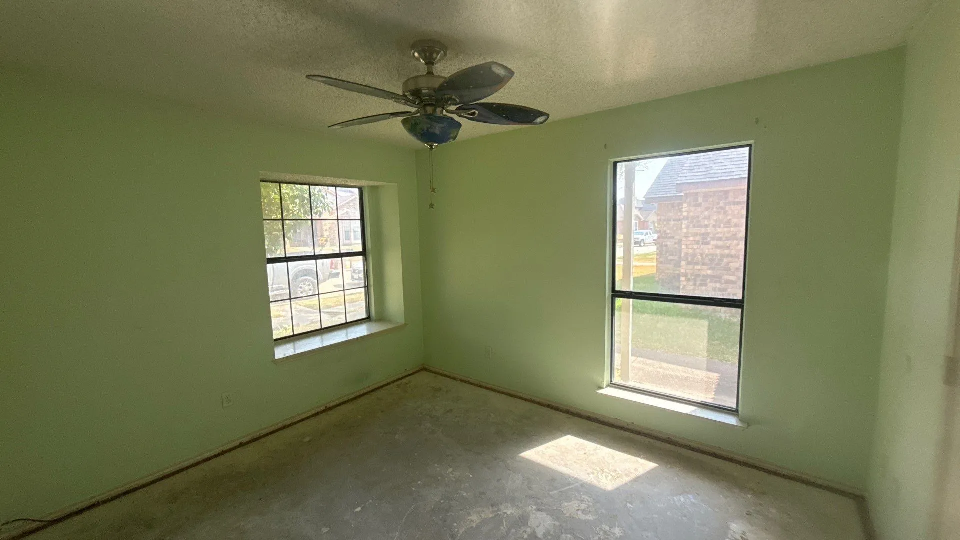 Two windows with sills, a ceiling fan with integrated lighting, and painted walls