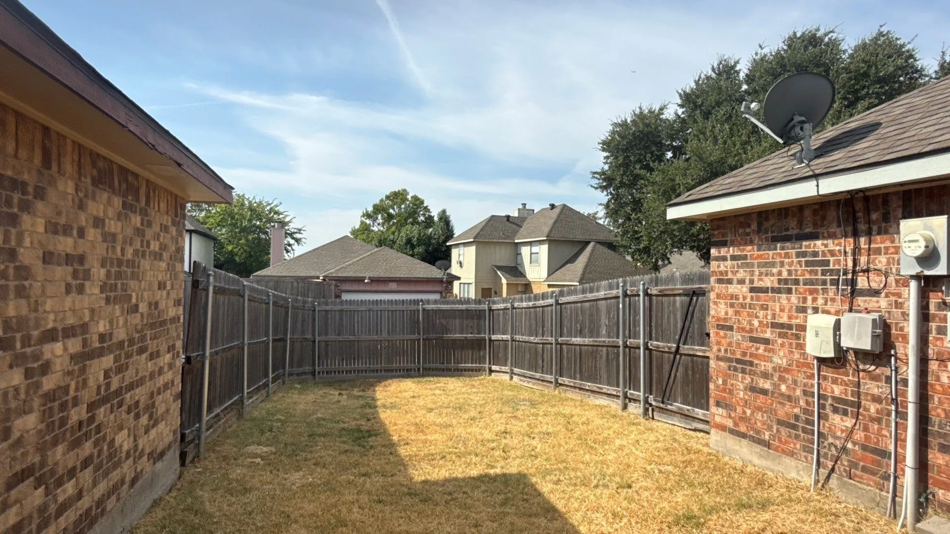 Private backyard space featuring a wood privacy fence and brick exterior