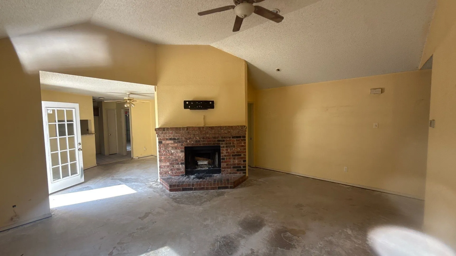 Vaulted ceiling, brick-surround fireplace, ceiling fan, and paneled glass door
