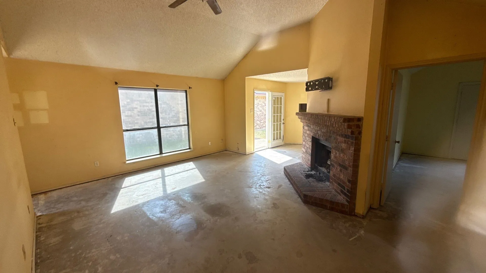 Vaulted ceilings, brick fireplace, French doors, ceiling fan, and large windows