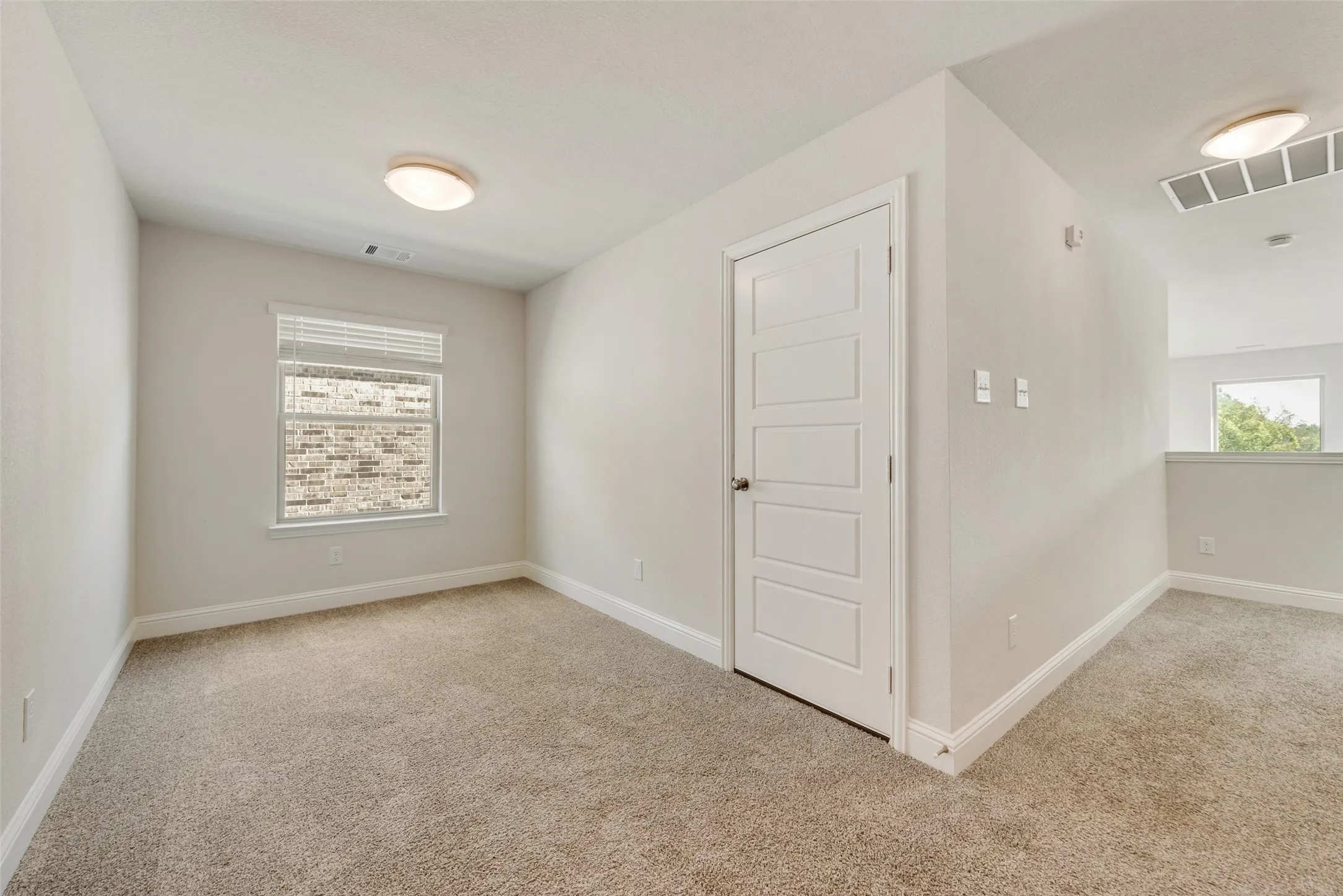 Carpeted room featuring a single window with blinds, a five-panel interior door, and flush-mount ceiling lighting