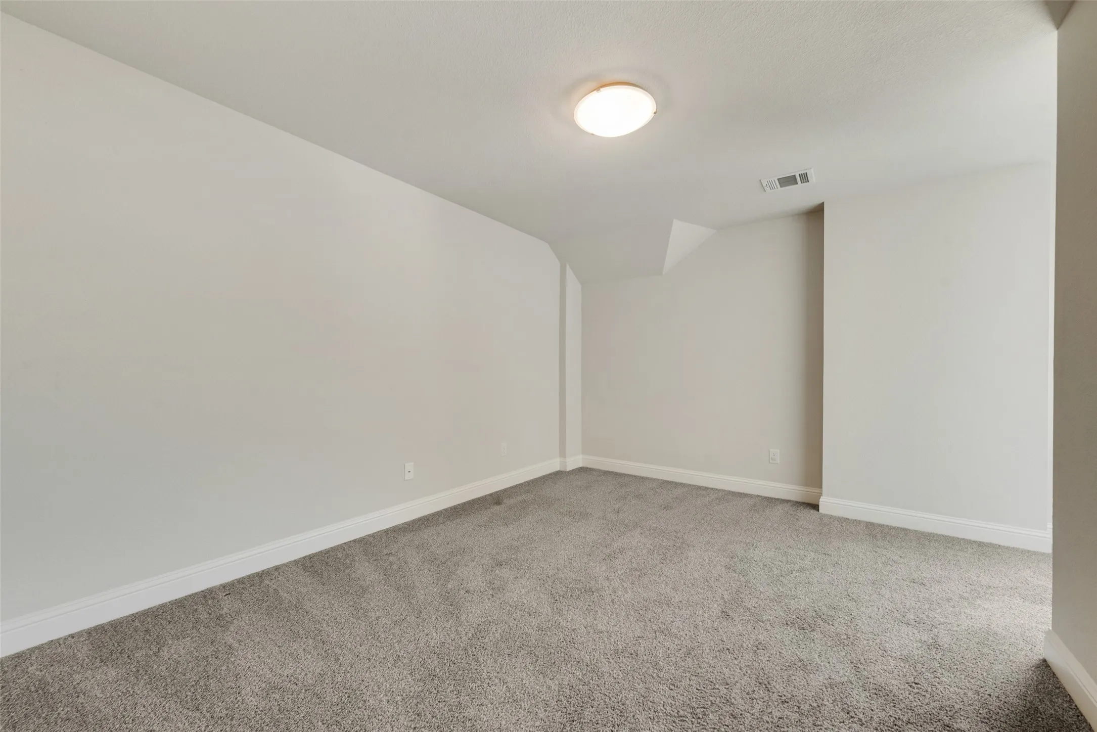 Neutral wall paint, recessed lighting, and grey carpeting