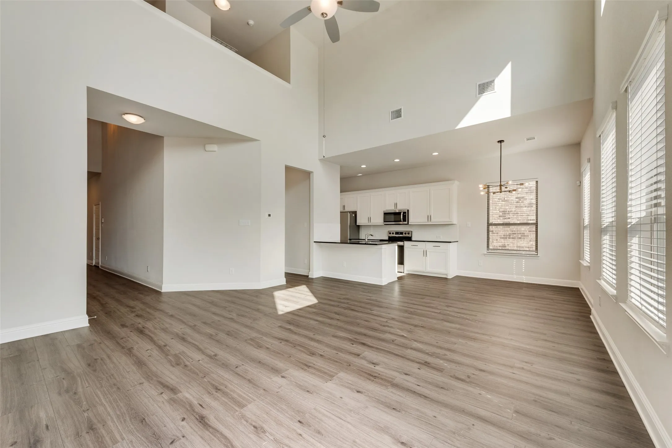 Vaulted ceilings, wood-finish flooring, white cabinetry, dark countertops, and stainless steel appliances