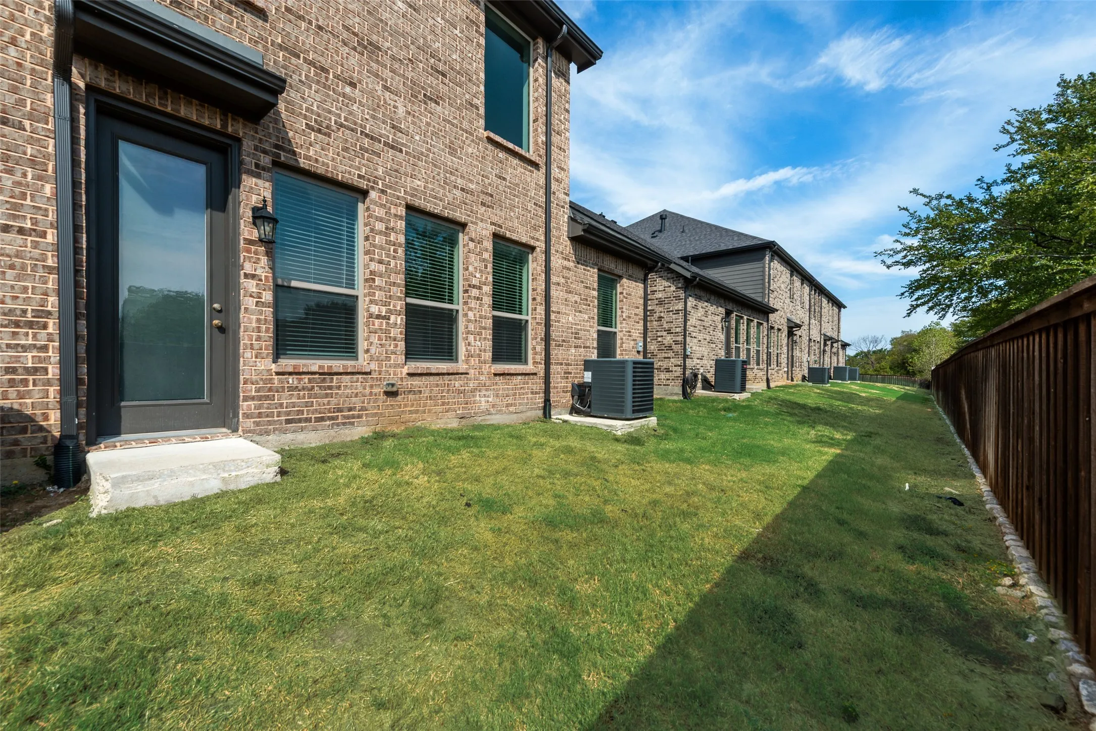 Brick exterior with multiple windows and a rear door leading to a grassy area