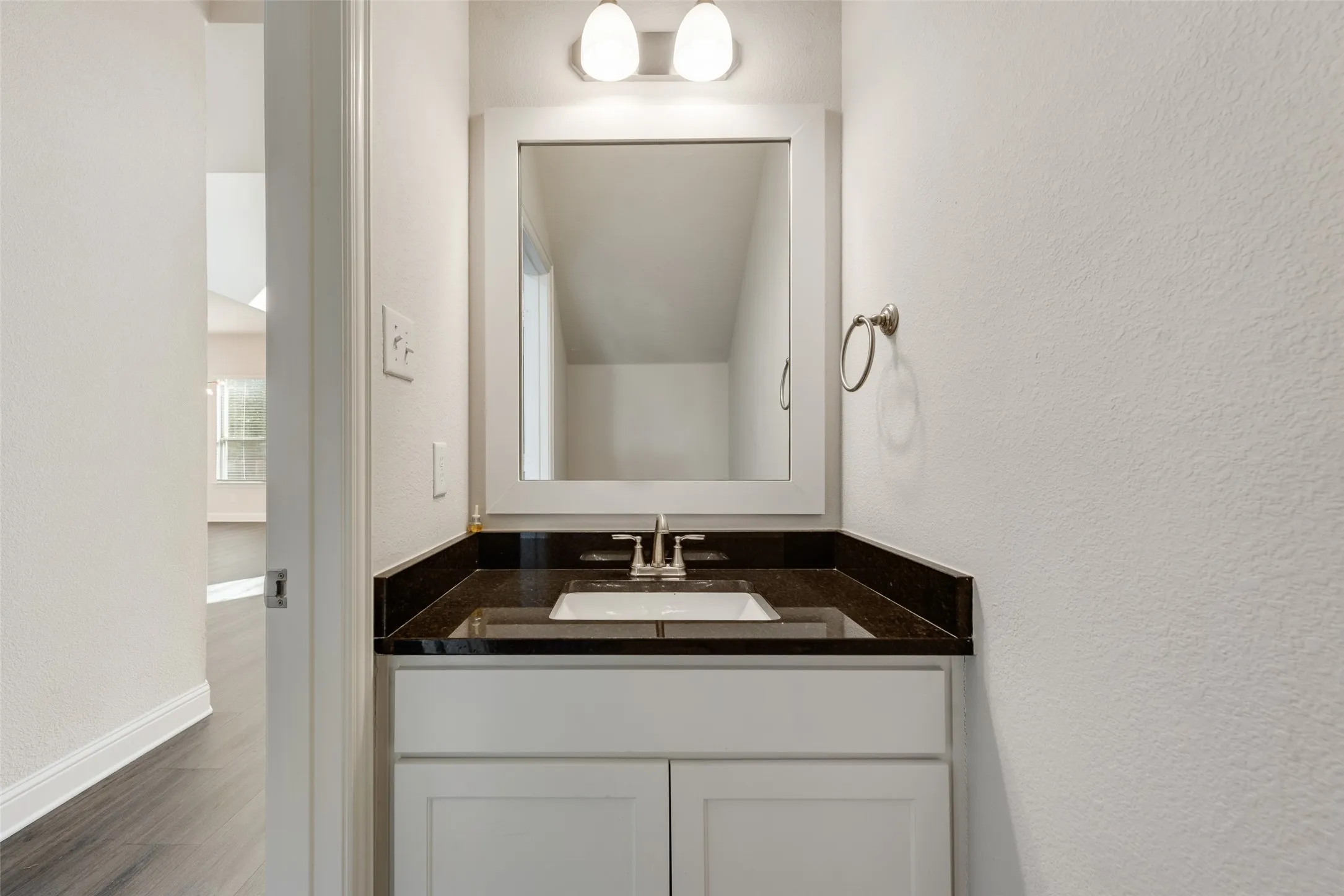 Single vanity with white cabinetry, a dark countertop, and an undermount sink