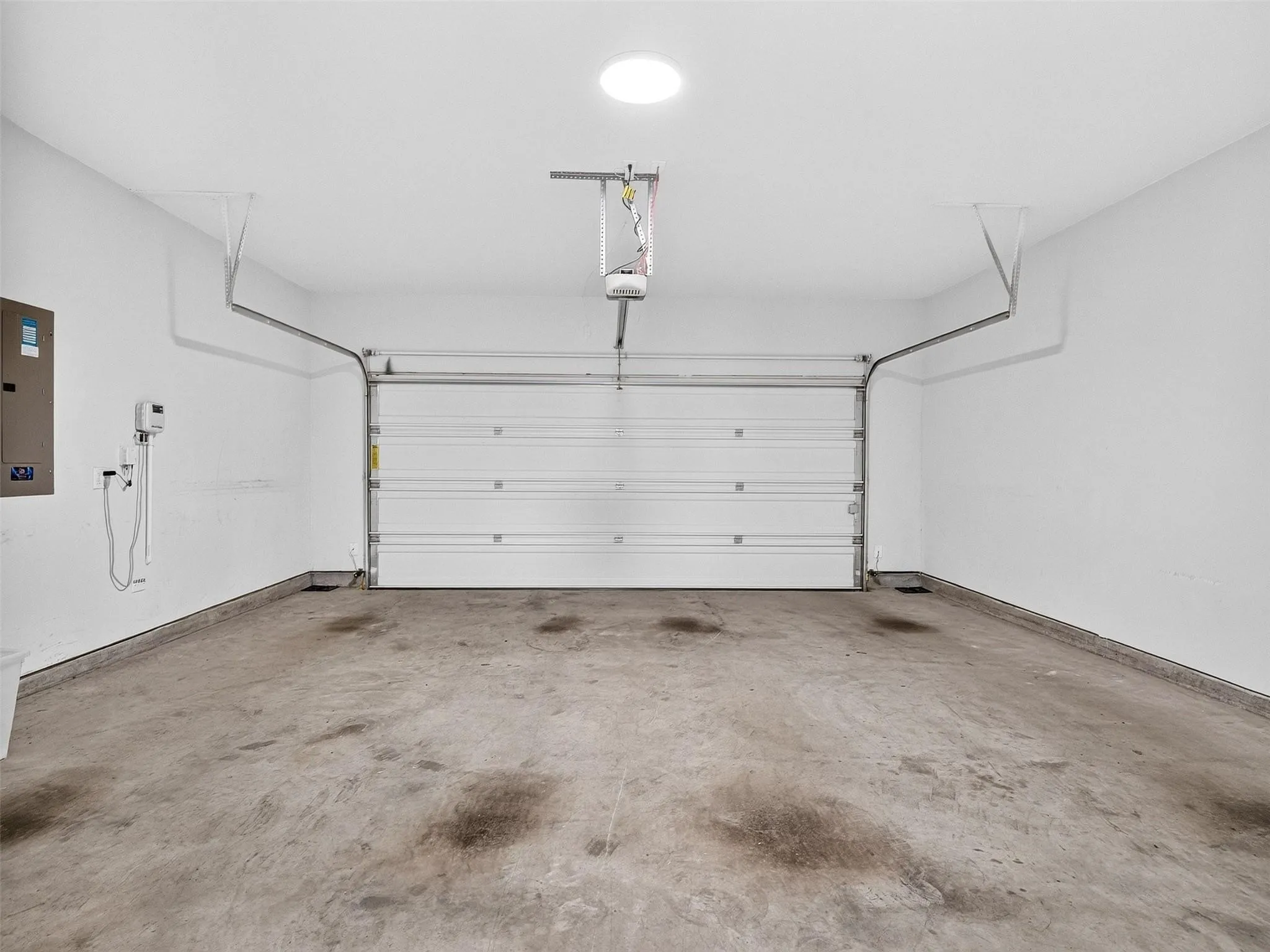 Garage space with concrete flooring, overhead lighting, and an automatic garage door opener