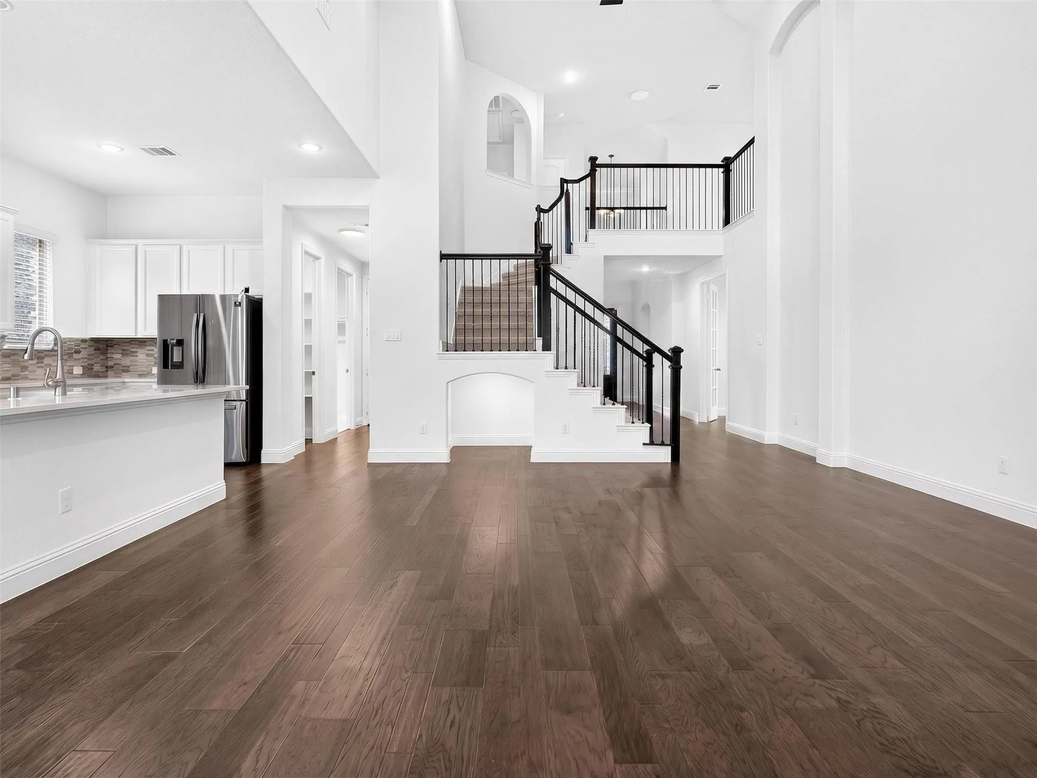 Soaring ceilings, rich wood-finish flooring, and a grand staircase with dark balusters