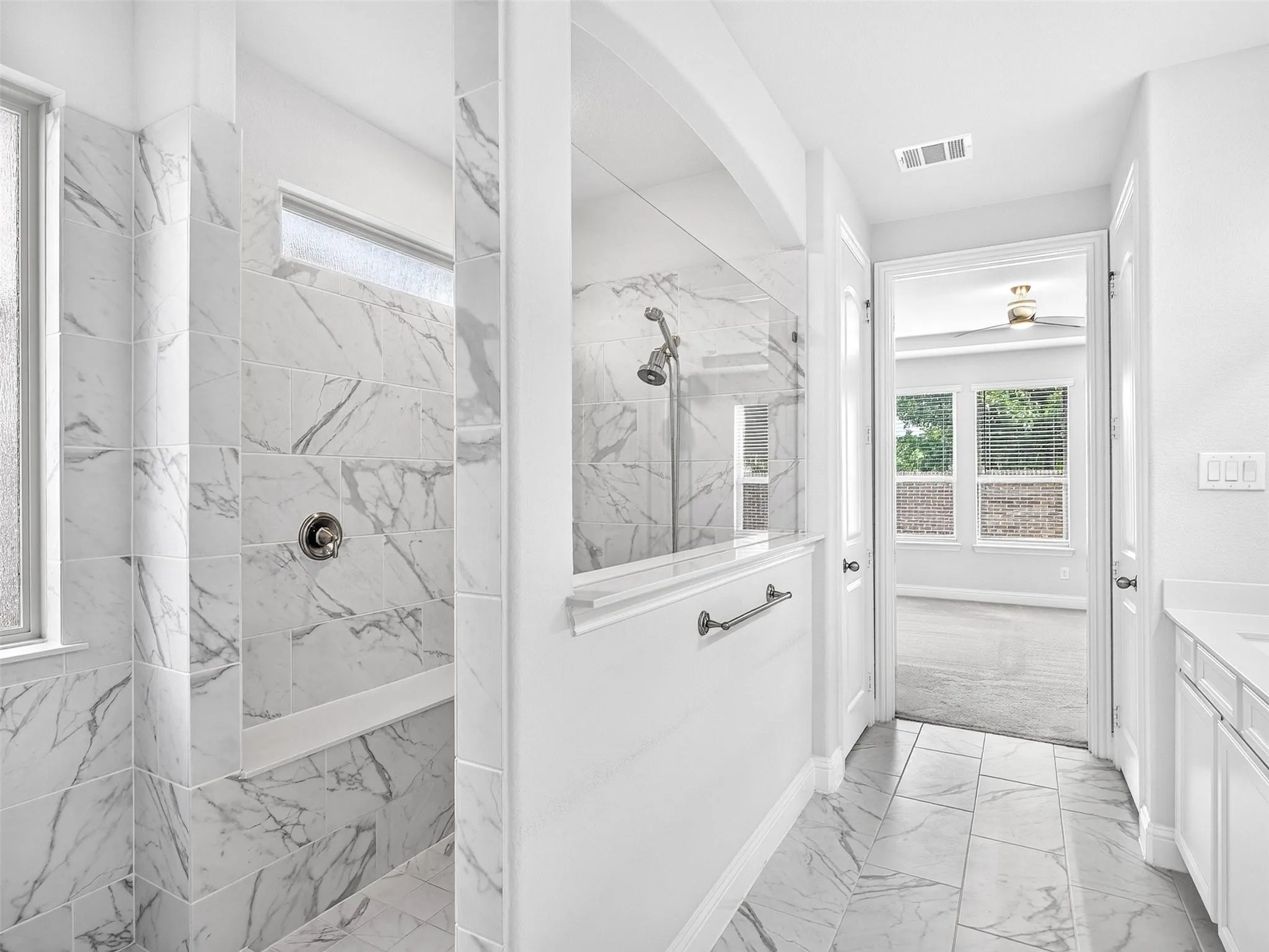 Walk-in shower with full-height tile surround, integrated shower bench, and a glass partition