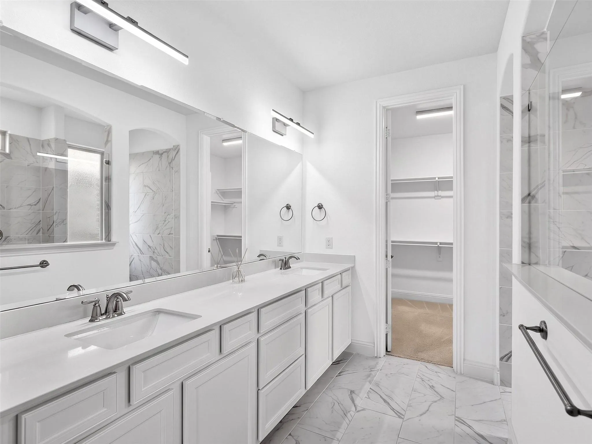 Dual vanity with white cabinetry, integrated sinks, and linear light fixtures