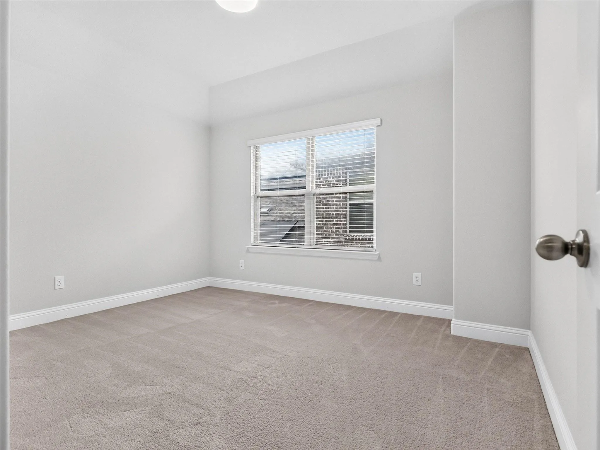 Neutral wall color, carpeted flooring, window with blinds, and white trim