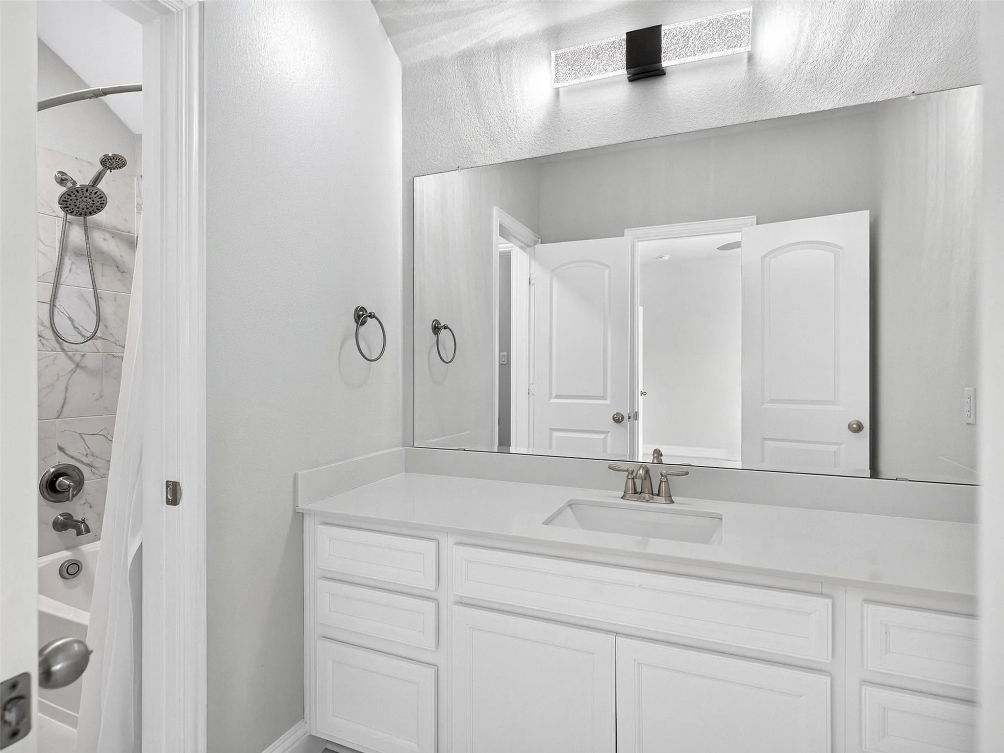 White vanity with integrated sink, brushed nickel faucet, and extensive countertop