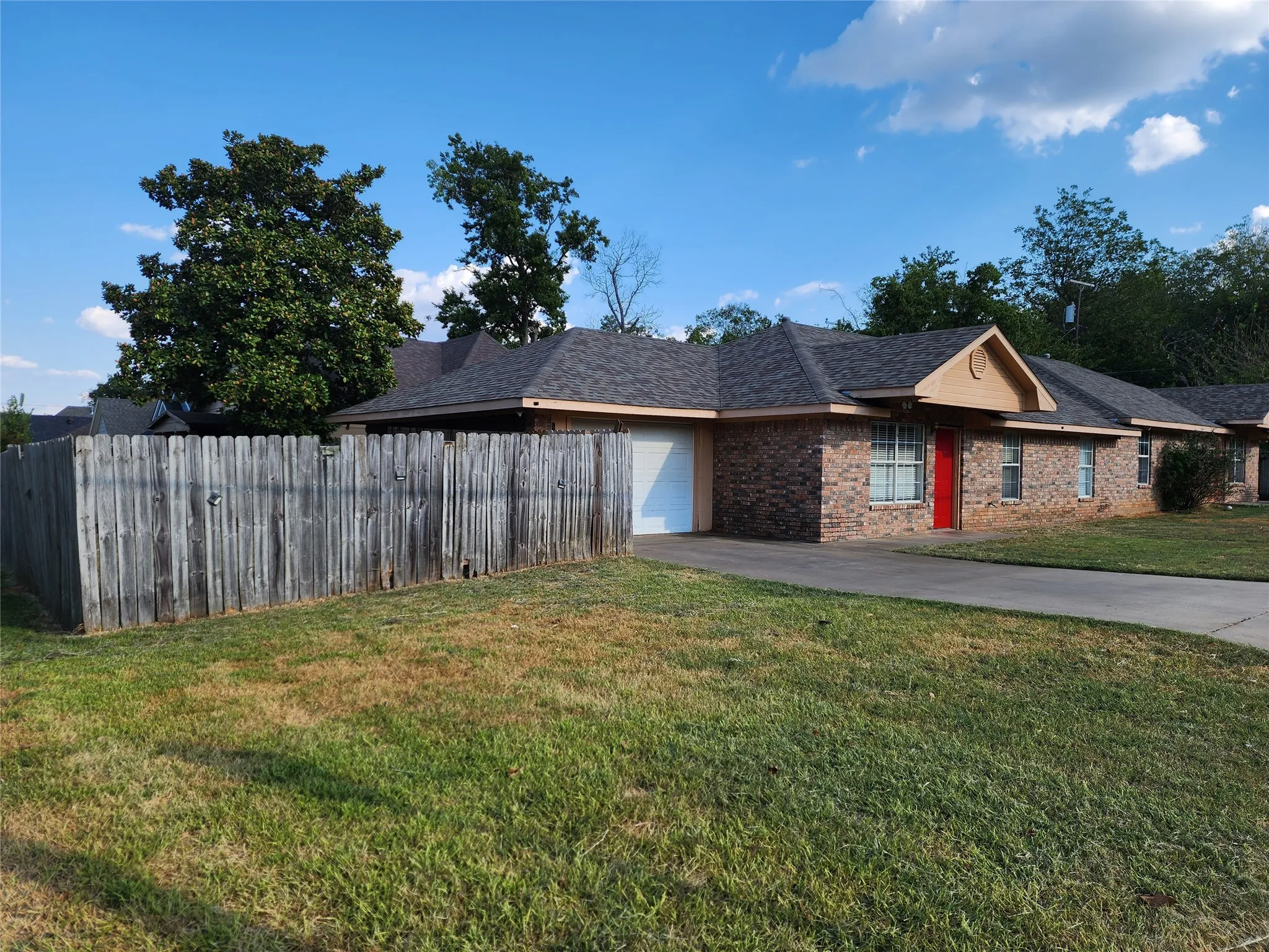 Brick exterior with a red front door, attached garage, and a peaked roofline