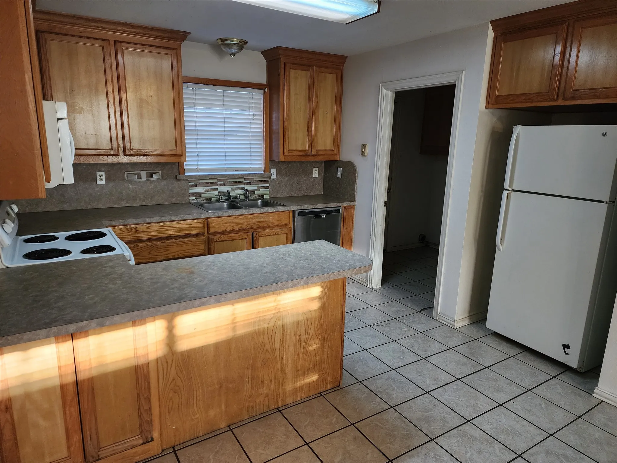 Kitchen featuring wood cabinetry, laminate countertops, tile flooring, and a breakfast bar