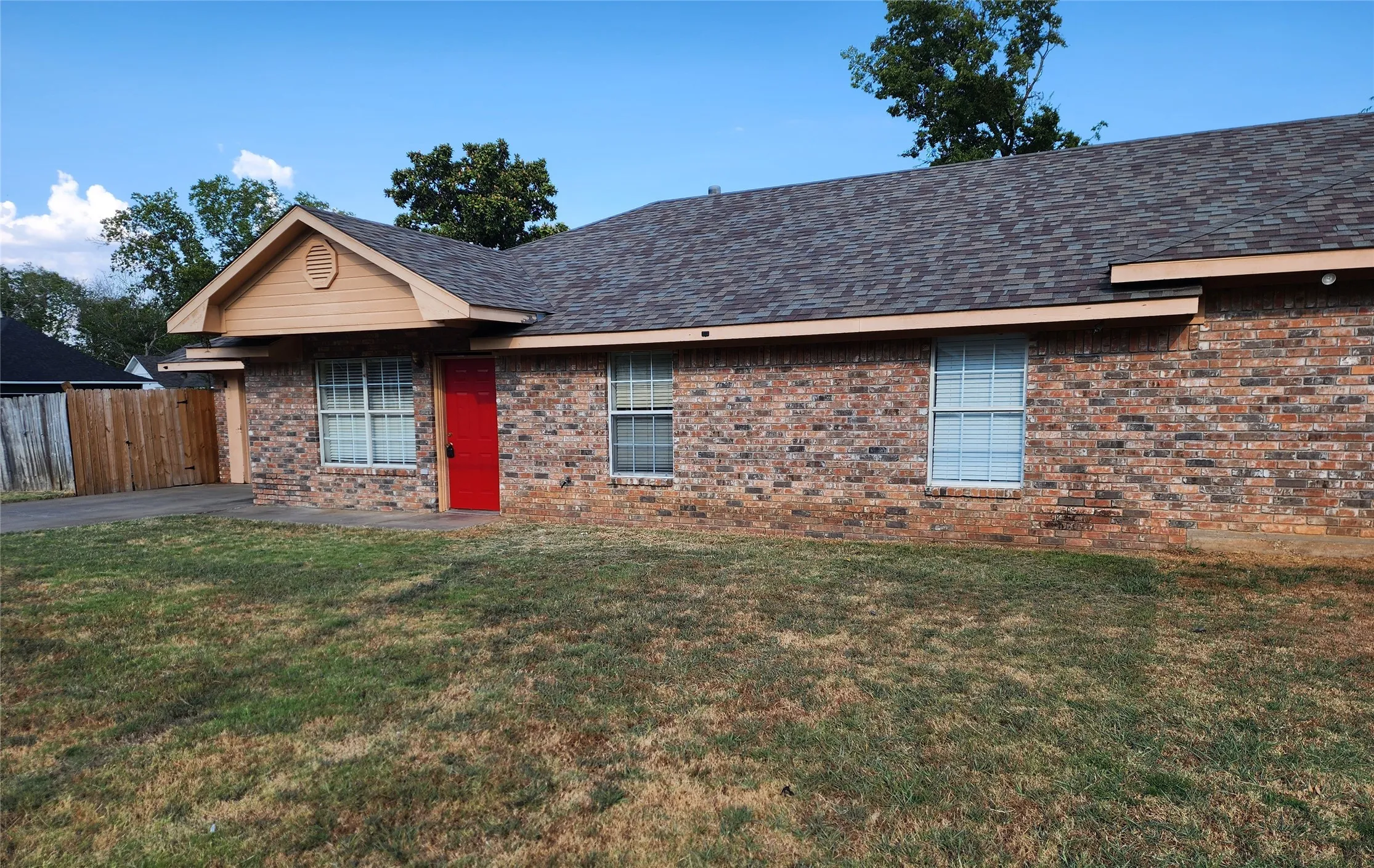 Brick exterior with a distinctive red entry door, framed by a gabled accent and covered entryway
