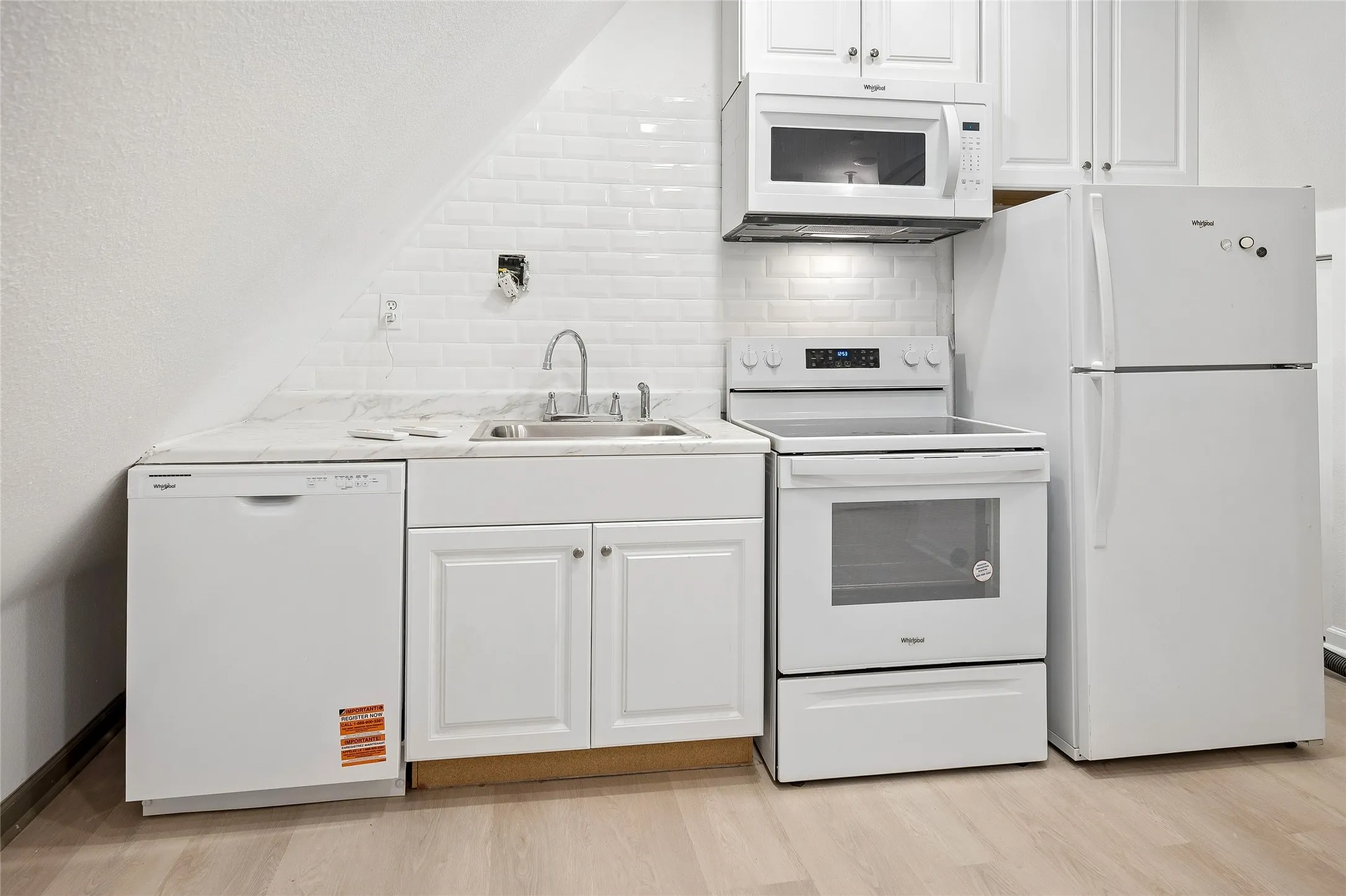 Full kitchen with wood floor, subway tile, appliances.