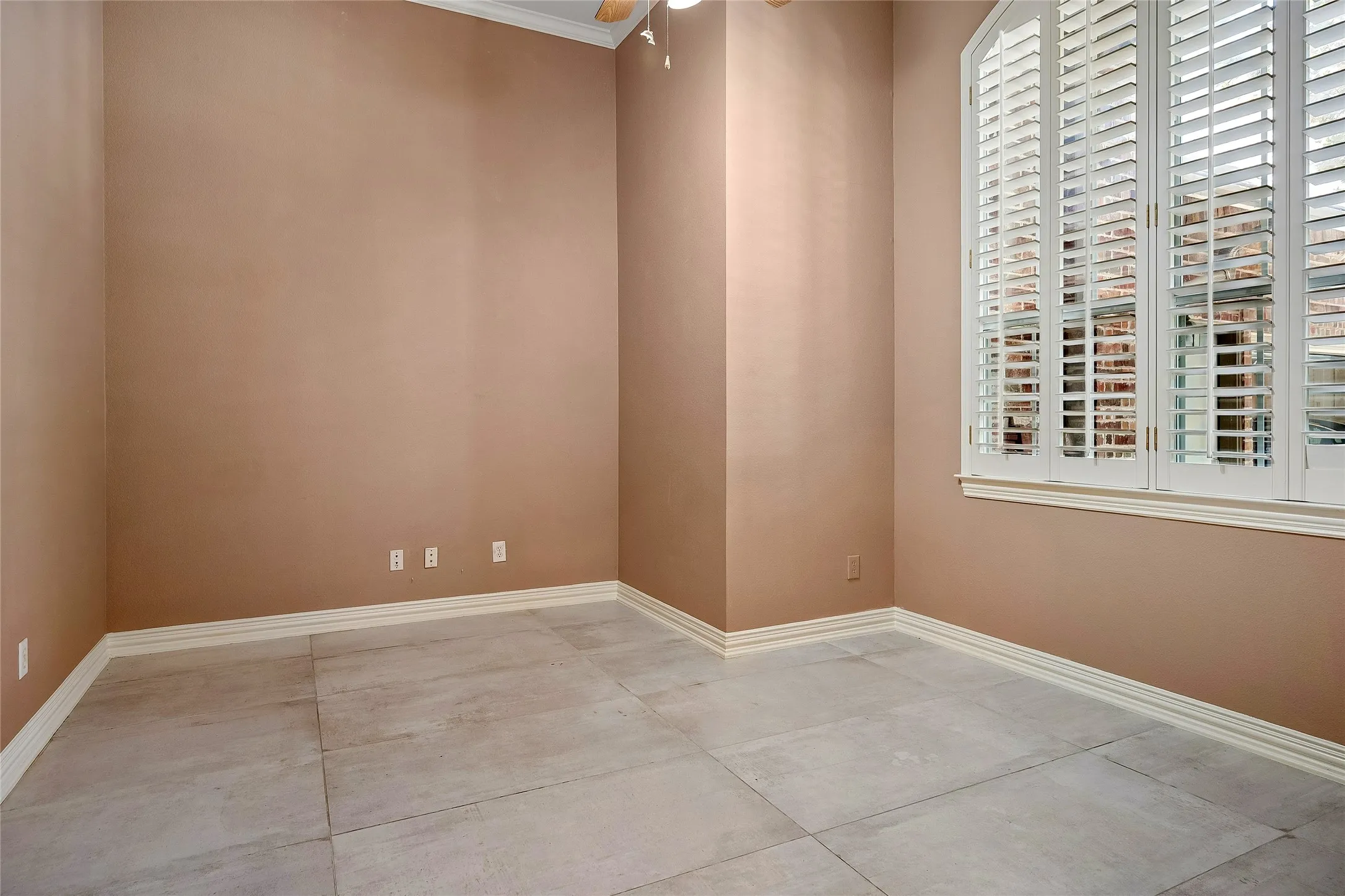 Secondary bedroom with ceiling fan, custom tile and custom windows with shutters.