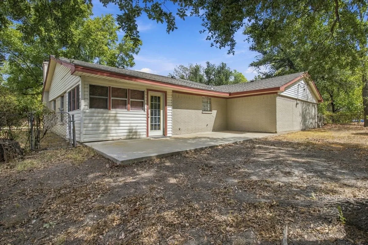 Back of home, large concrete back patio, sunroom entry, mature trees in back yard